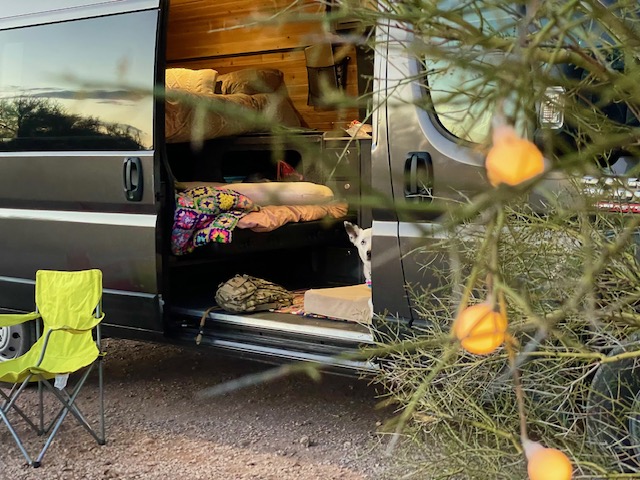 A comfortable RV rental setup for van life, featuring a cozy interior, a dog peering out, and an outdoor chair.. RAM Promaster SUMMIT X Edition OA11 2021