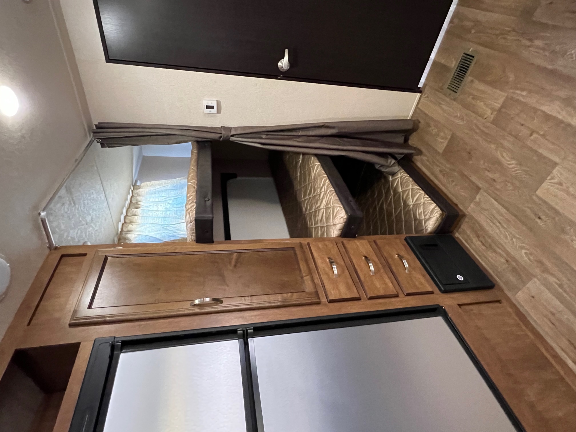 Explore this RV rental's interior: comfy bunk beds, sleek refrigerator, and warm wood cabinetry. Ideal for road trips.. Forest River Salem 2018