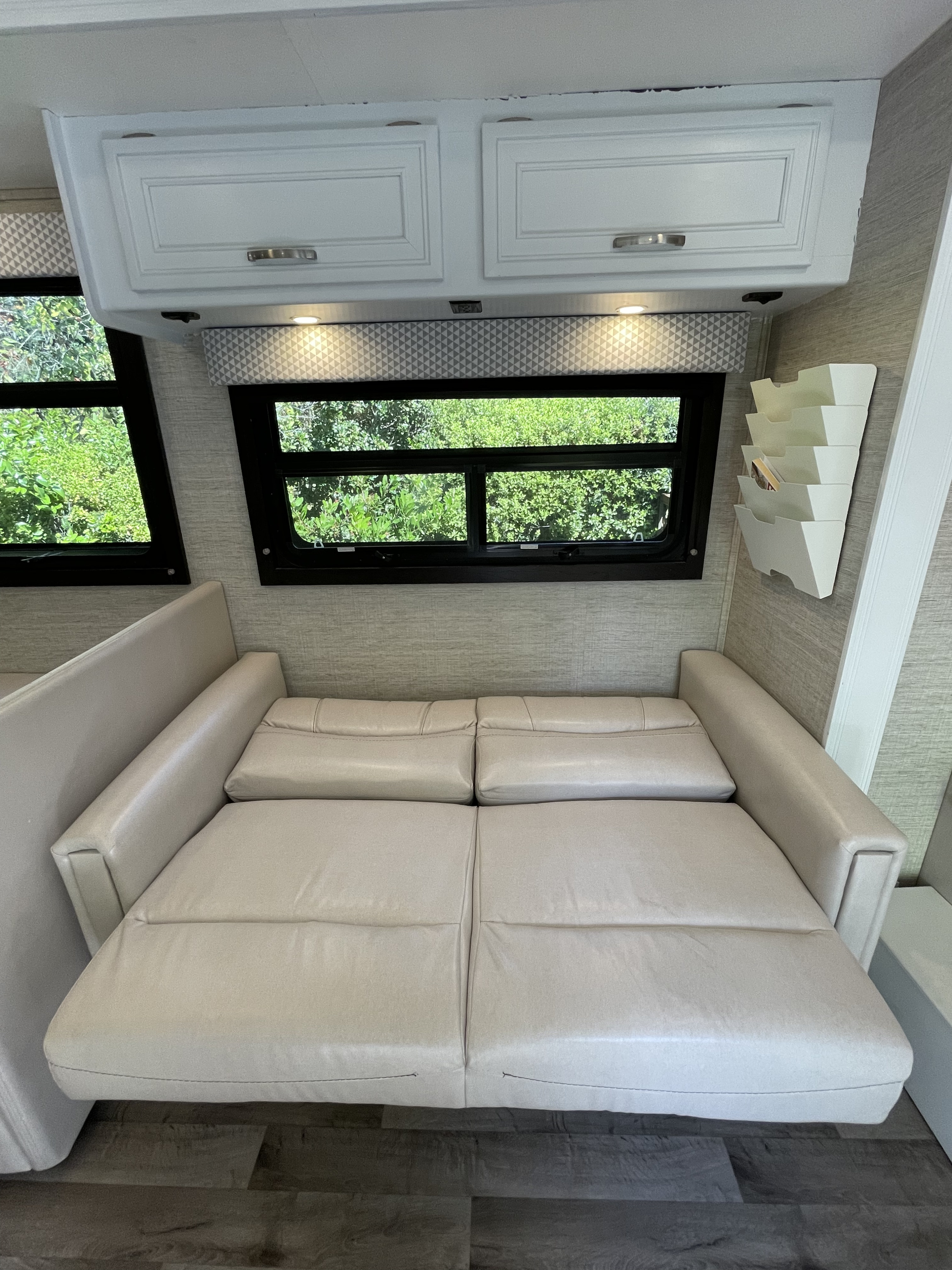 Relax in this RV rental's extended sofa, offering comfortable sleeping. Overhead cabinets and bright windows complete the cozy interior.. Jayco Redhawk 2021