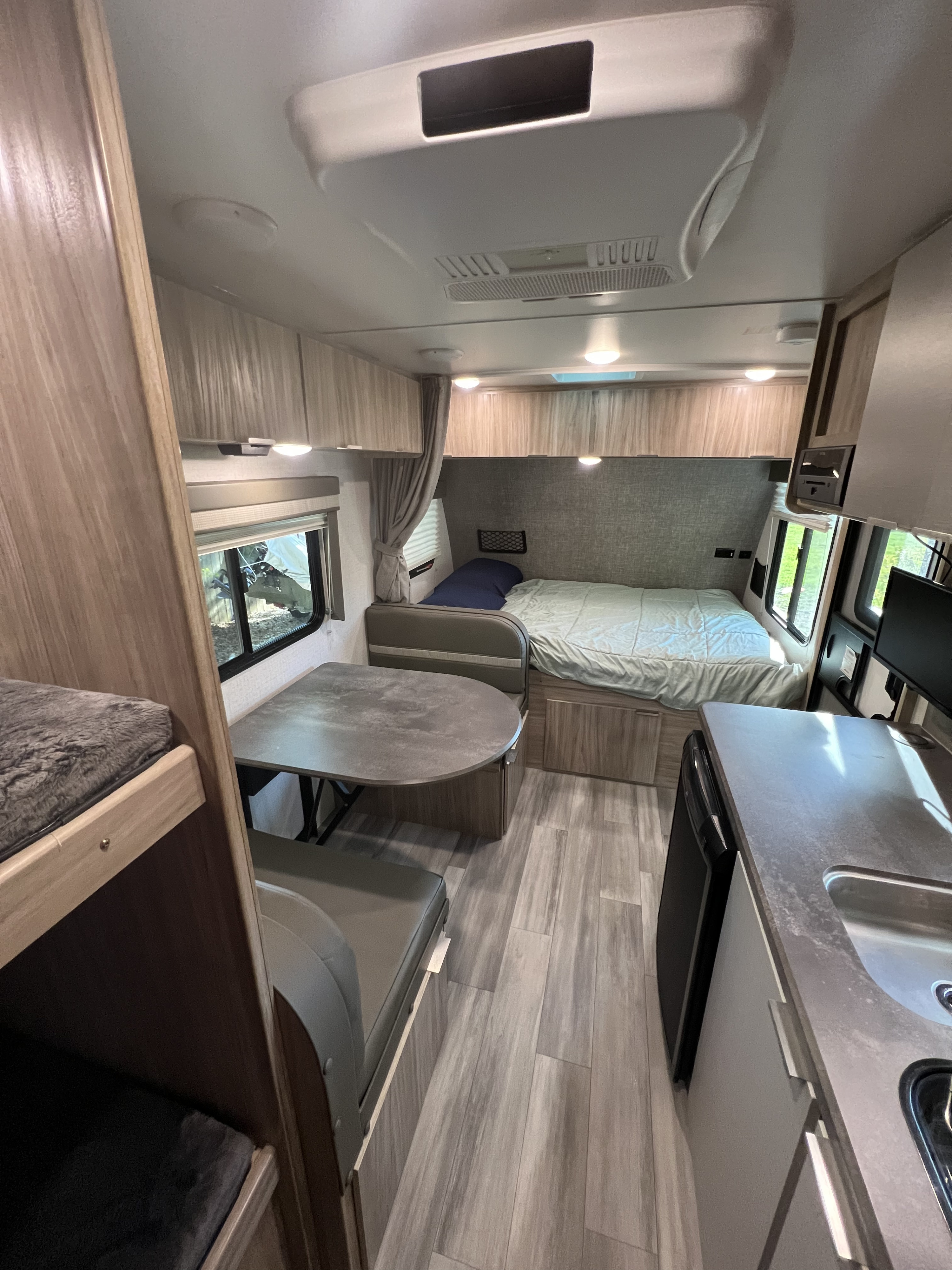 Inside a well-appointed RV rental, showing bunk beds, dinette, a comfortable main bed, and kitchenette with a sink.. Winnebago Micro Minnie 2021