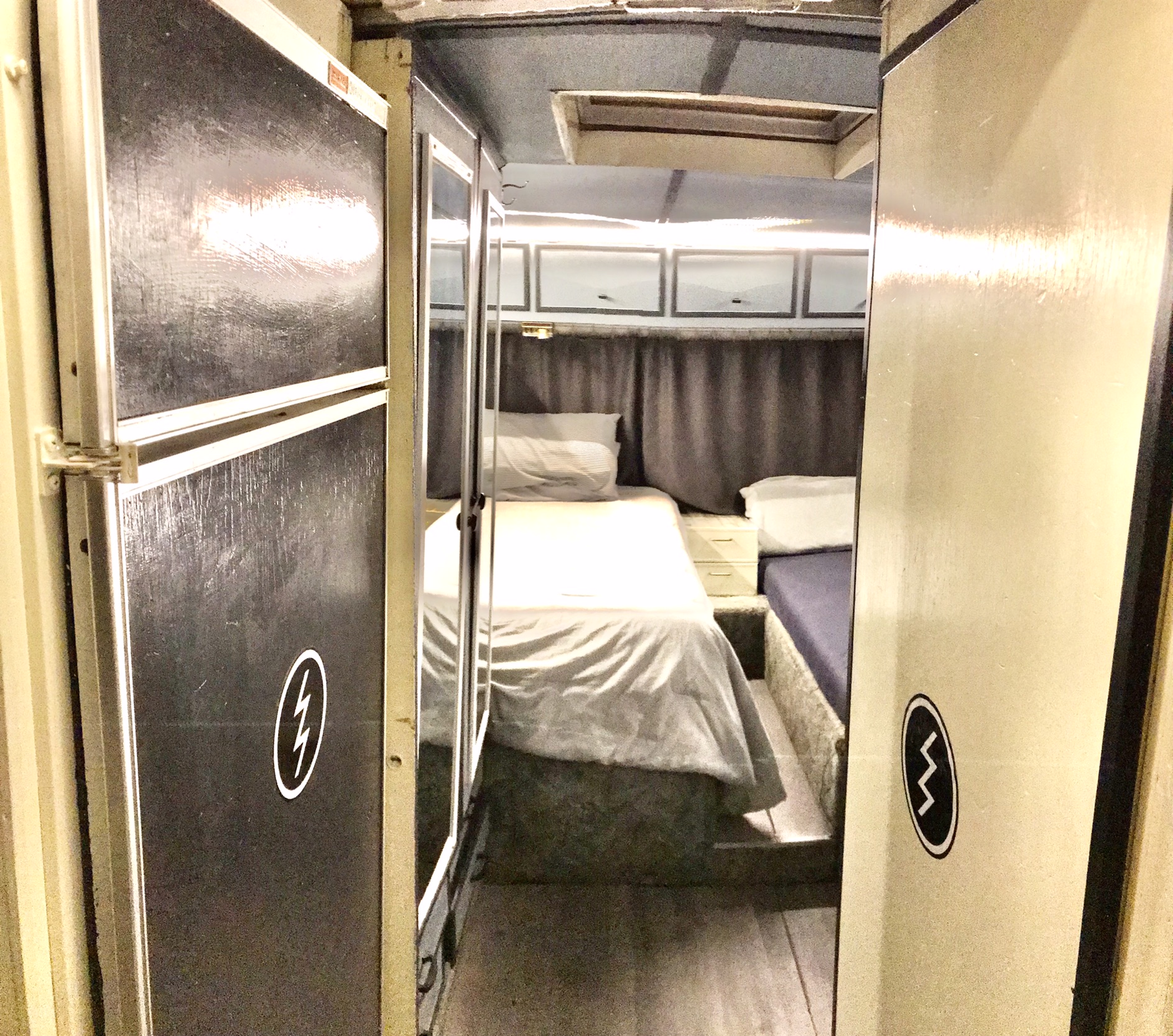 This RV rental offers a cozy sleeping area with two twin beds, overhead cabinets, and a narrow central aisle.. Dodge Commander 1974