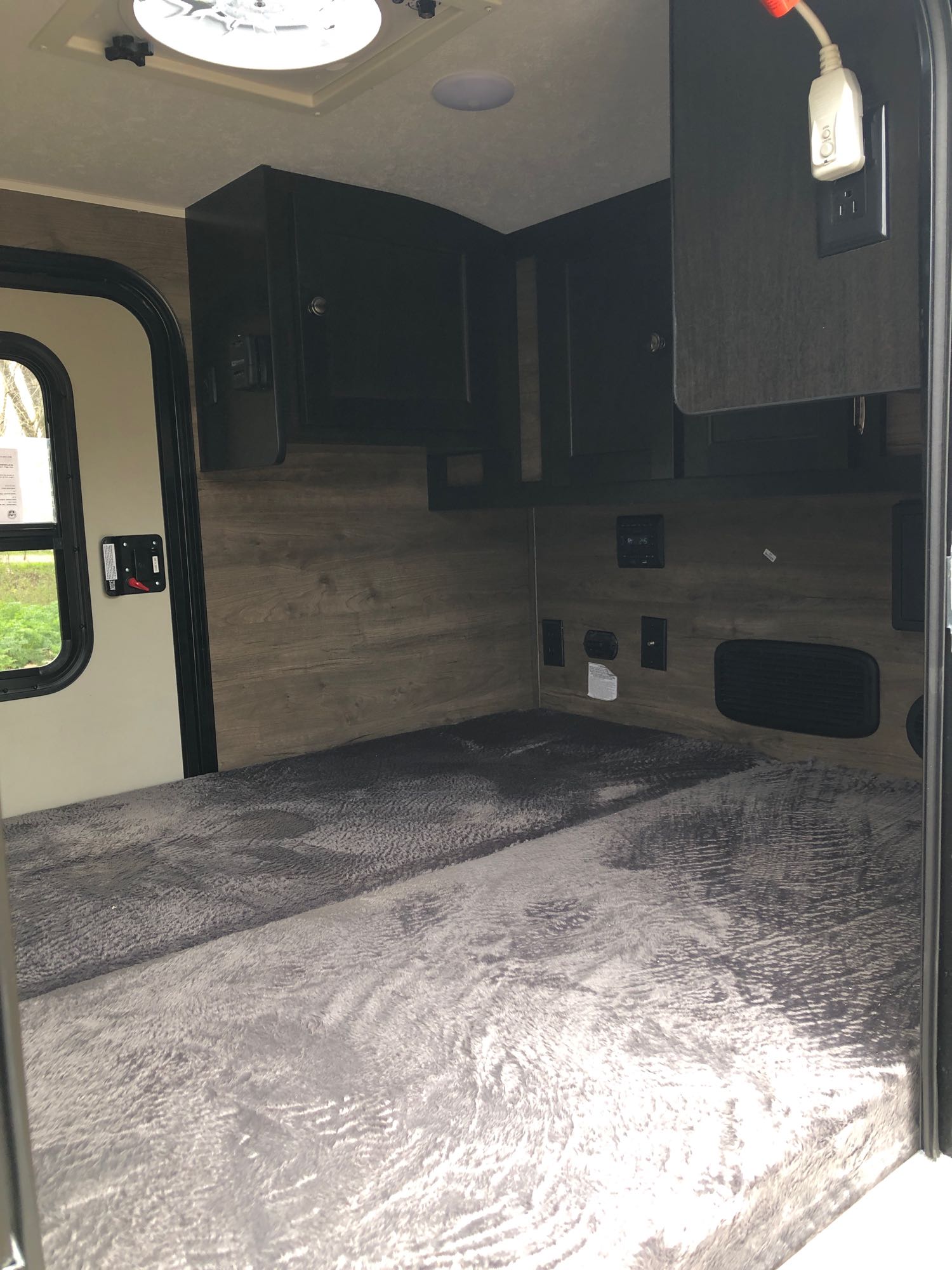 Cozy RV rental interior with a comfy gray bed, overhead cabinets, power outlets, and a window for a comfortable stay.. Braxton Creek Bushwhacker 2022