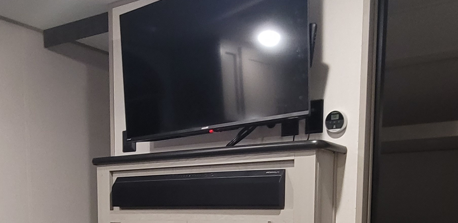 RV rental: View of an RV entertainment setup featuring a TV, soundbar, and digital thermostat.. Forest River Tracer 2022