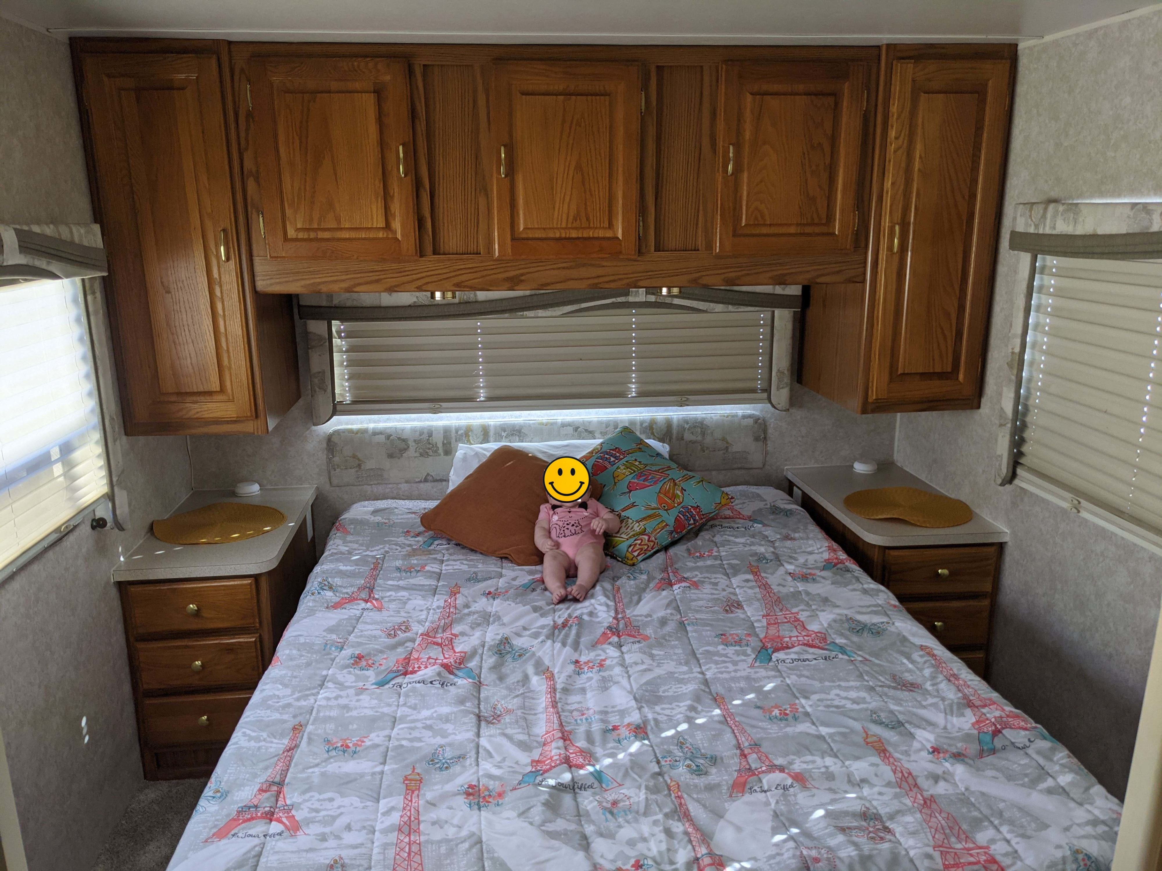 Cozy RV rental bedroom featuring ample wooden storage cabinets, a bed with Eiffel Tower bedding, and bedside tables.. Jayco Eagle 2001