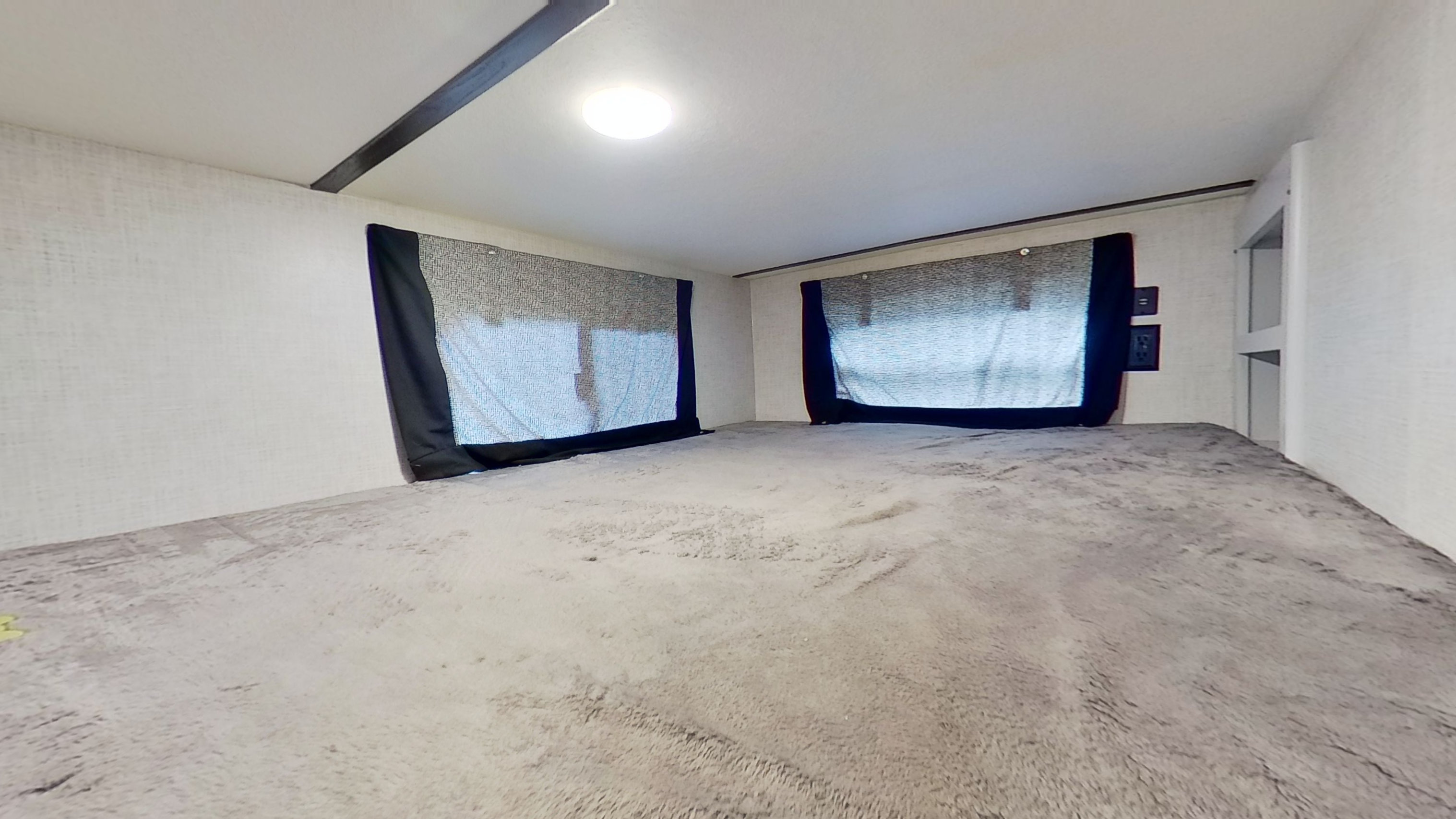Spacious RV rental bunk with plush grey bedding, privacy shades, and ceiling light for a comfortable sleep.. Keystone RV Bullet Ultra Lite 2021