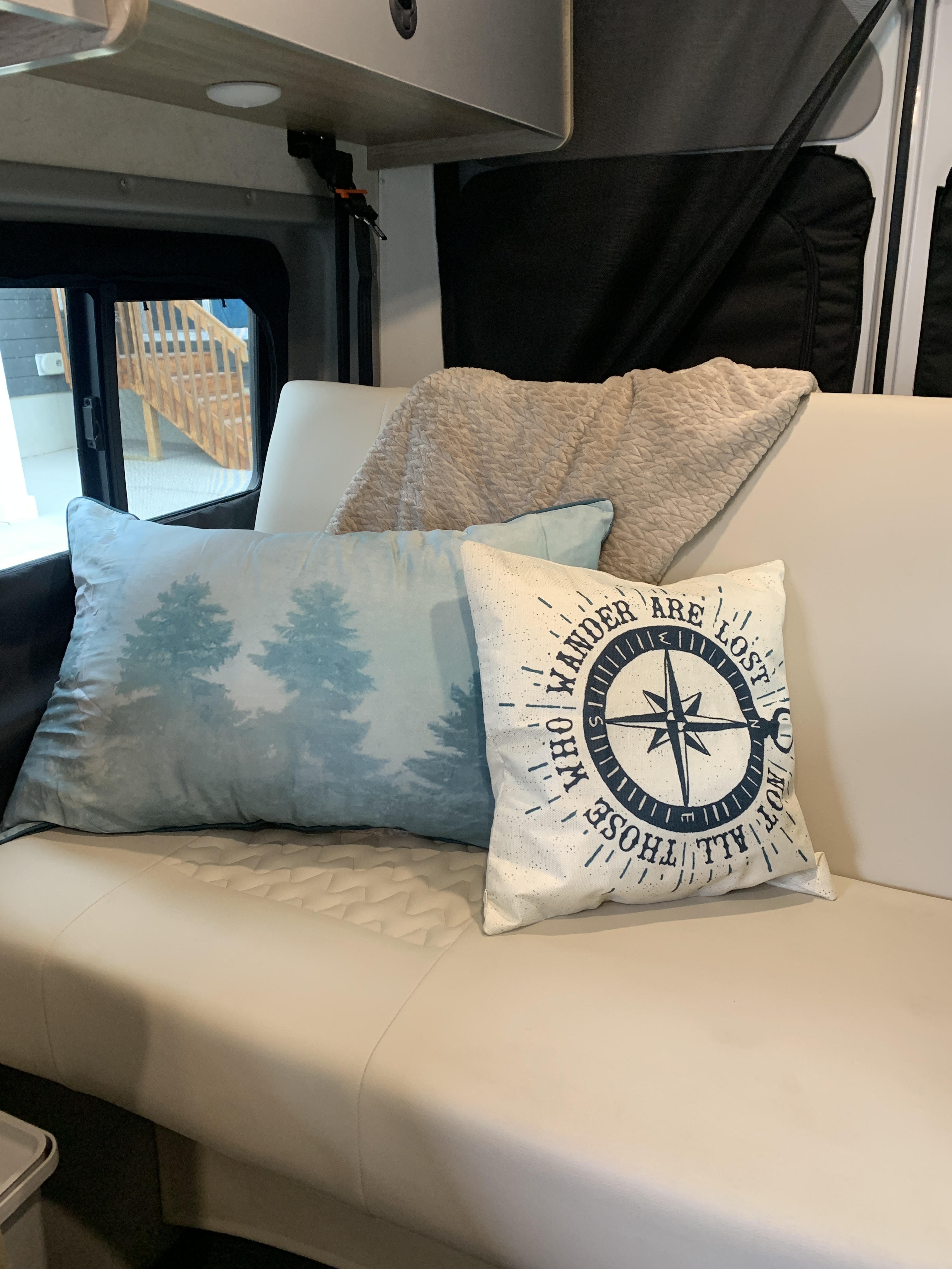 Cozy RV rental interior with pillows and blanket on a comfortable sofa, perfect for your next adventure.. Winnebago Solis 2021