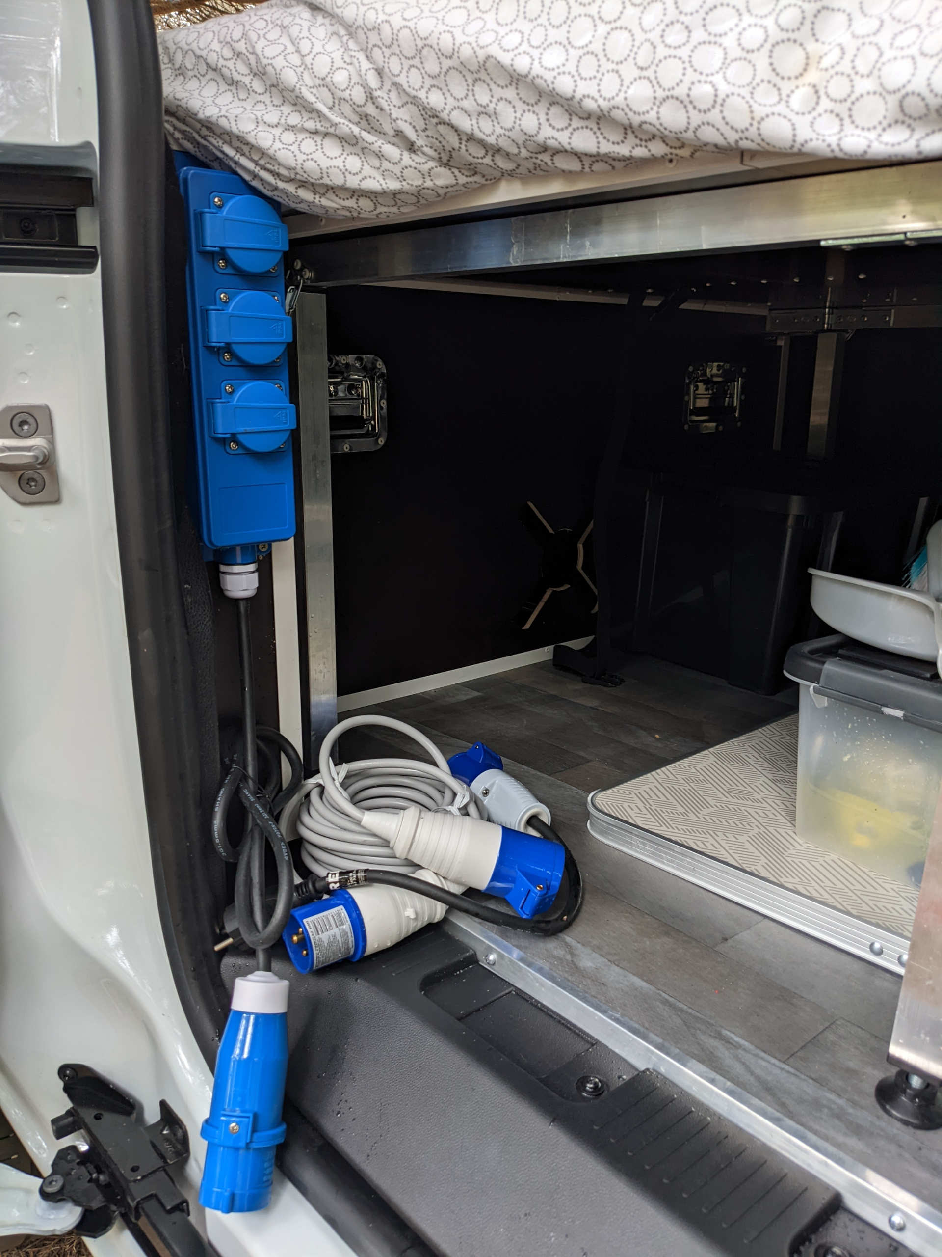 RV rental interior: blue power strip, electrical cables, and under-bed storage for travel setup.. Renault Kangoo 2021
