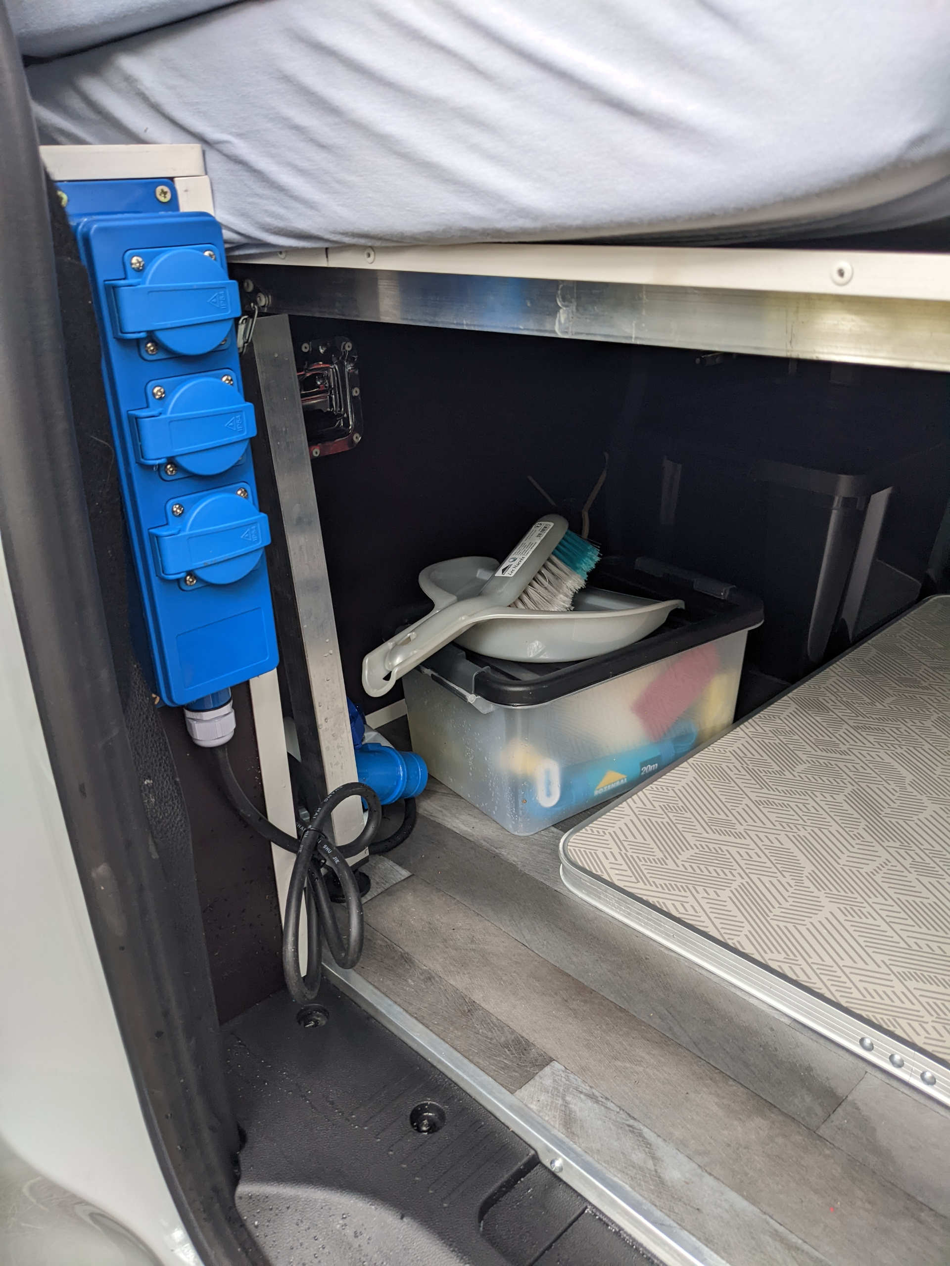 View inside an RV rental showing a blue power strip, organized storage, and a sleeping berth.. Renault Kangoo 2021