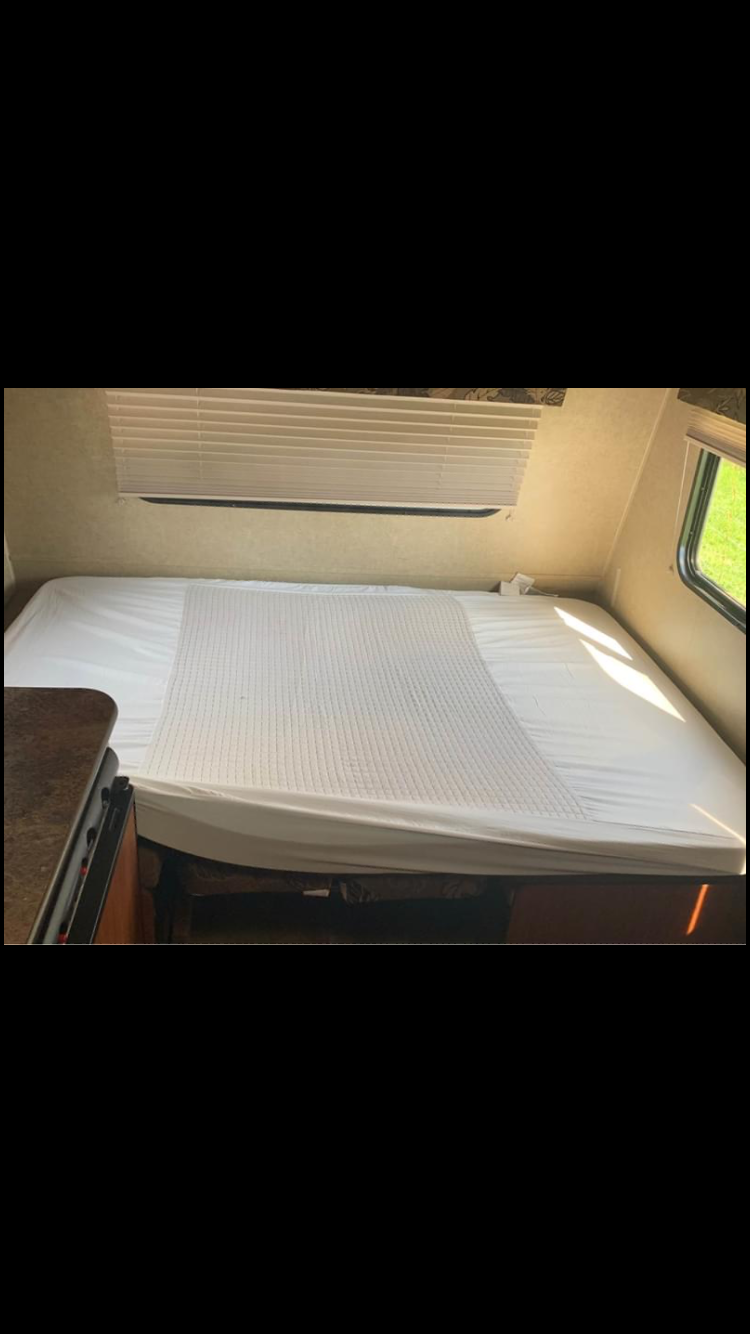 Comfortable RV rental sleeping area with fresh white linens and window blinds, perfect for your next travel adventure.. Jayco Bambi 2014