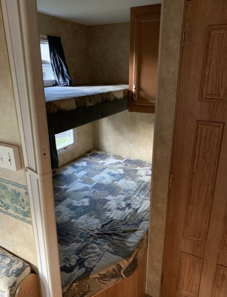 Inside an RV rental, a set of bunk beds features patterned mattresses and windows, offering a compact sleeping area.. Jayco Monarch 2007
