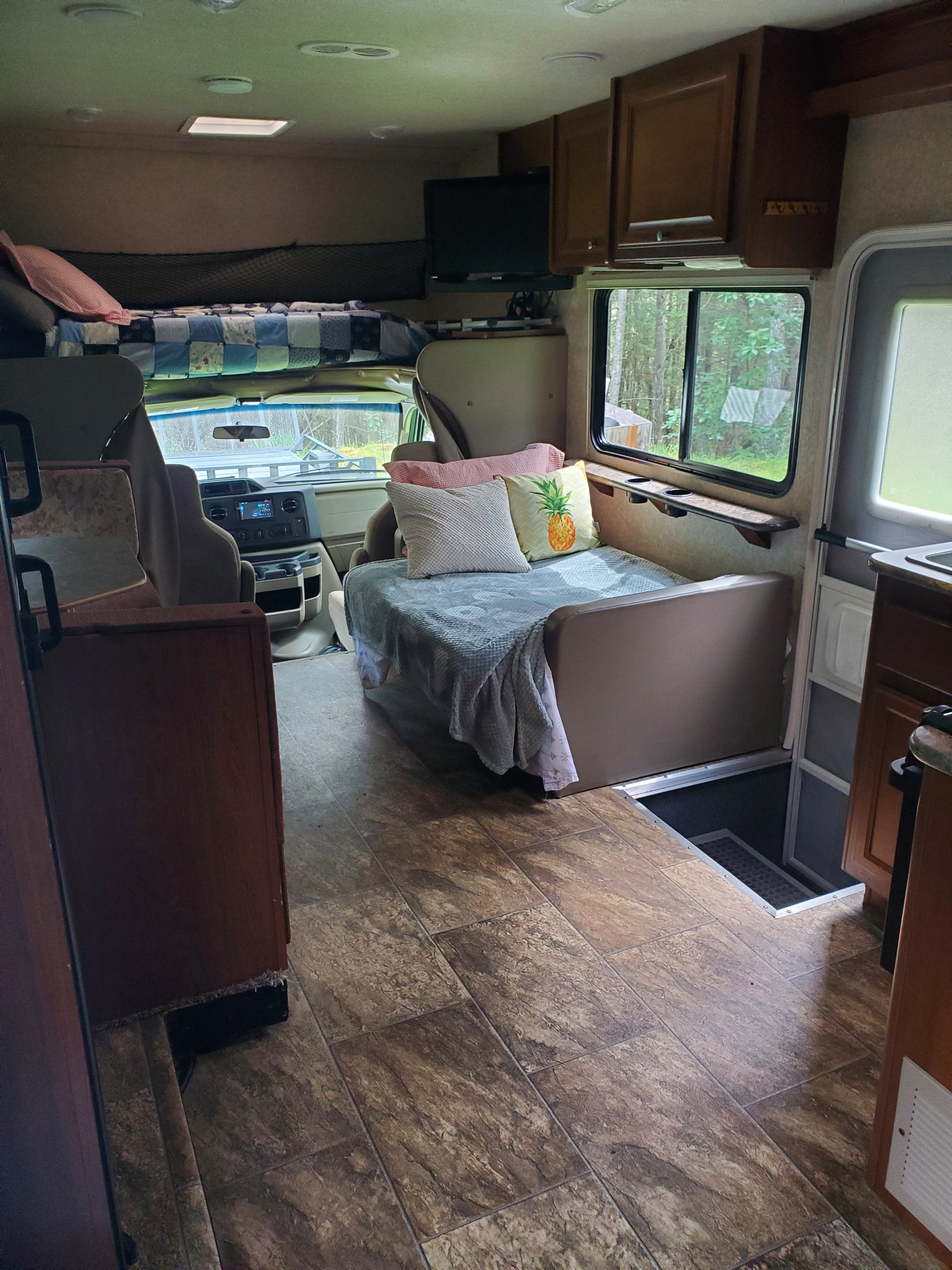 View inside an RV rental showing a comfy bunk, dinette area, and driver's cabin. Includes overhead storage & floor access.. Jamboree Searcher 2014