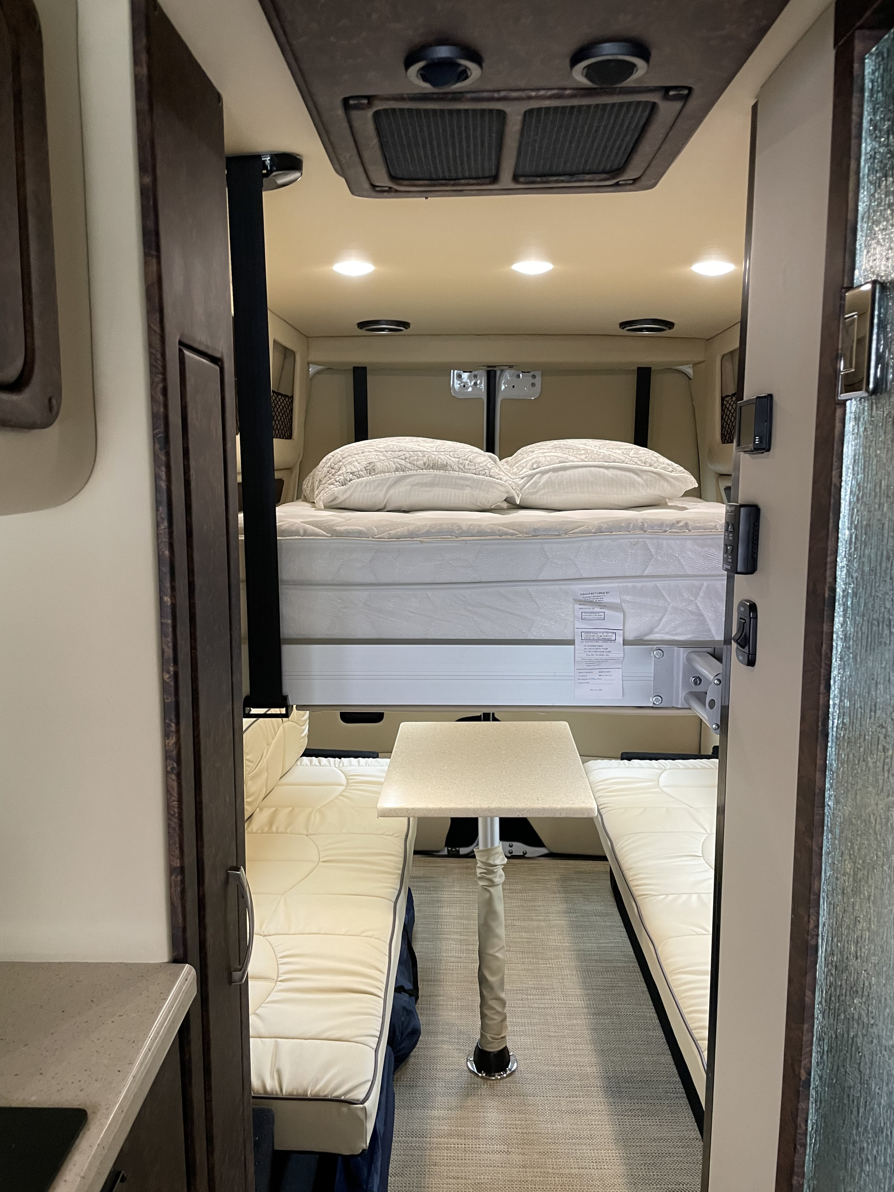 Compact RV rental interior featuring a drop-down bed and versatile dining/seating area. Perfect for camper travel.. Midwest Automotive Designs Midwest Automotive Designs Class B 2020
