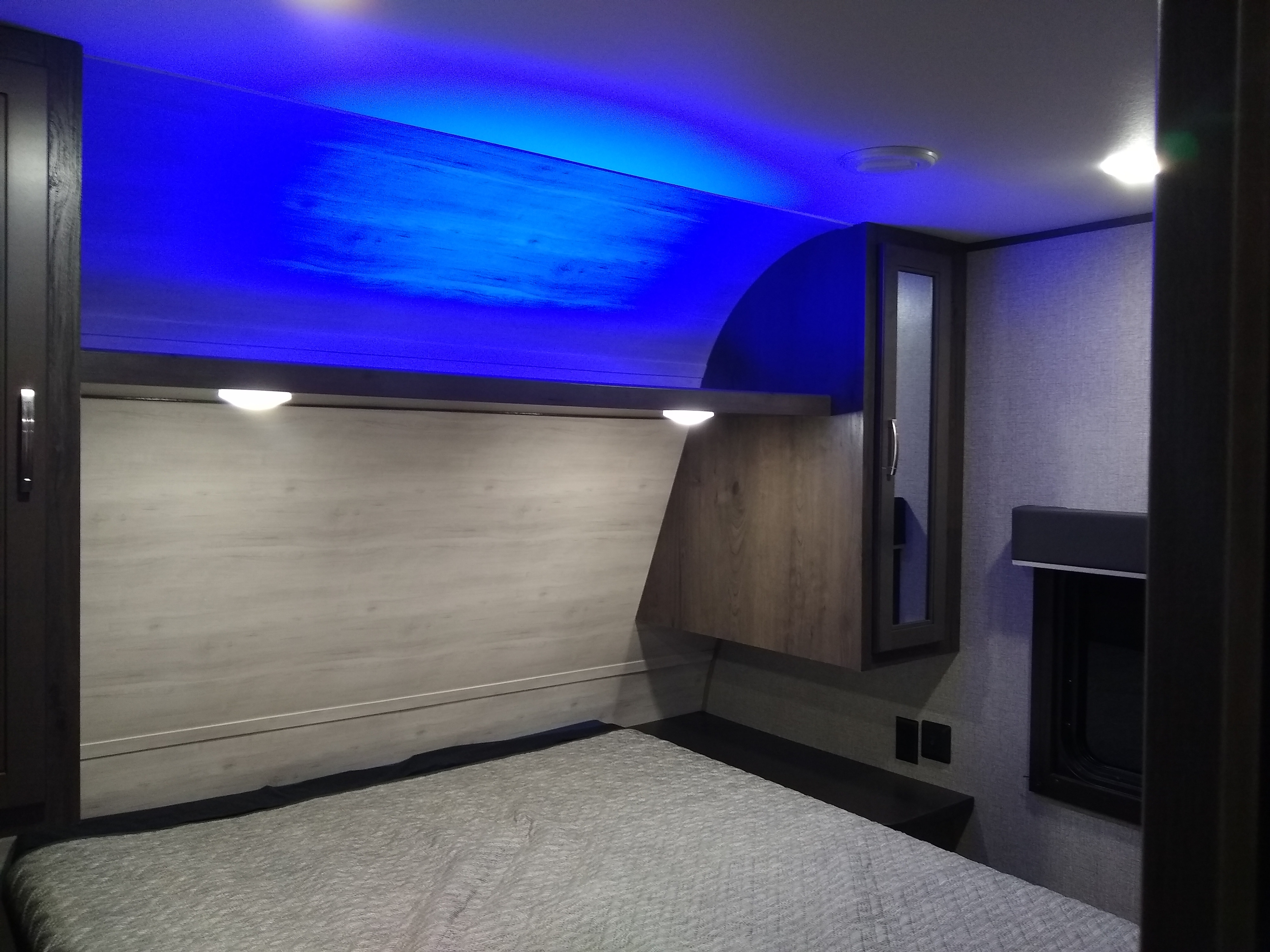 Experience comfort in this modern RV rental bedroom with ambient blue lighting, a cozy bed, and practical storage.. Jayco Jay Flight SLX 2021