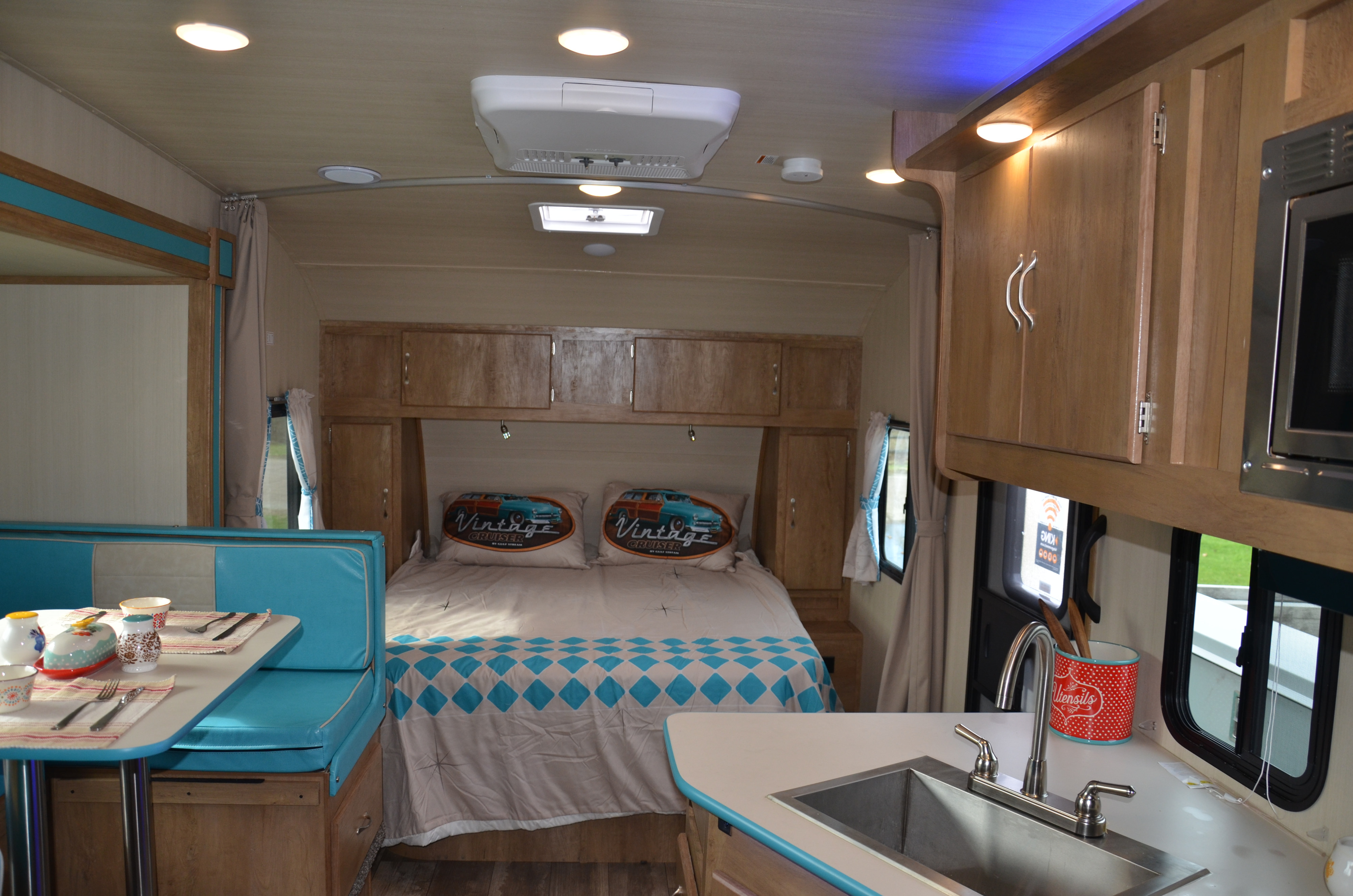 Cozy RV rental interior with a comfy bed, blue dinette, and functional kitchen. Ideal for road trip adventures.. Gulf Stream Vintage Cruiser 23 QBS 2022