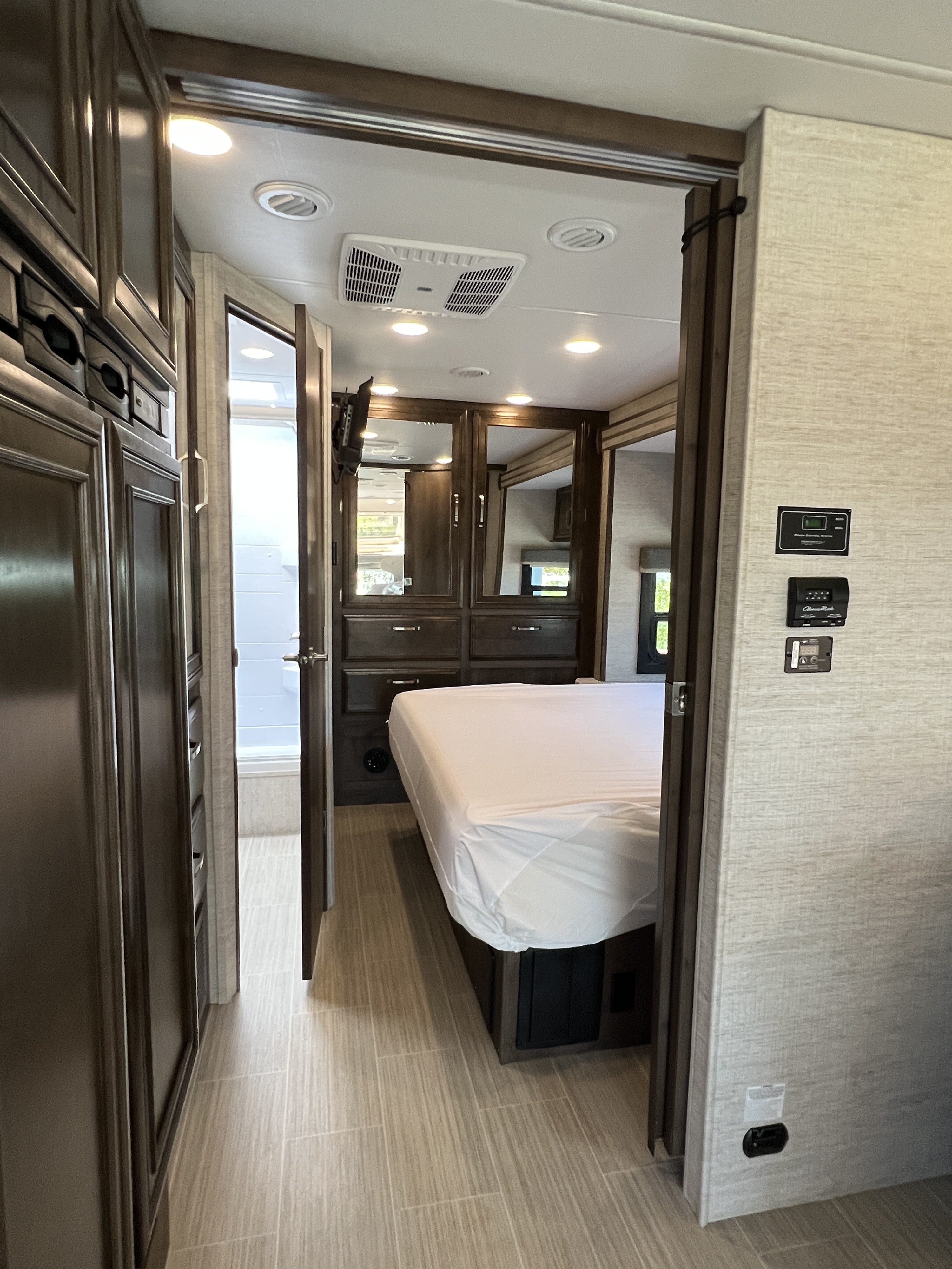 RV rental interior: Spacious bedroom with a bed, mirrored wardrobe, connected to a modern bathroom and hallway.. Entegra Coach Esteem 2022