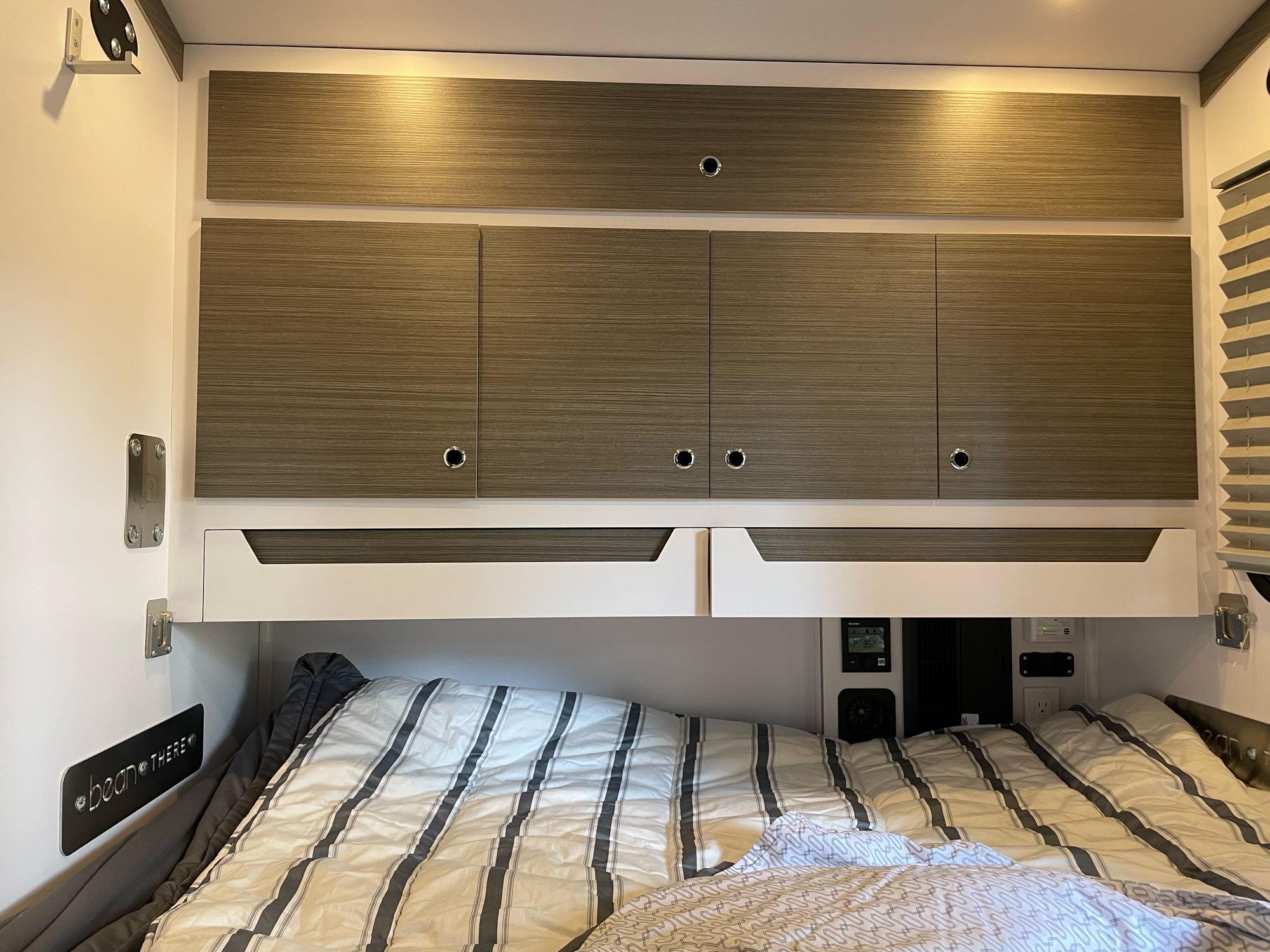 Cozy RV rental interior with a comfortable bed, wood-grain overhead storage cabinets, and ambient lighting, perfect for travel.. Bean Mean Bean 2022