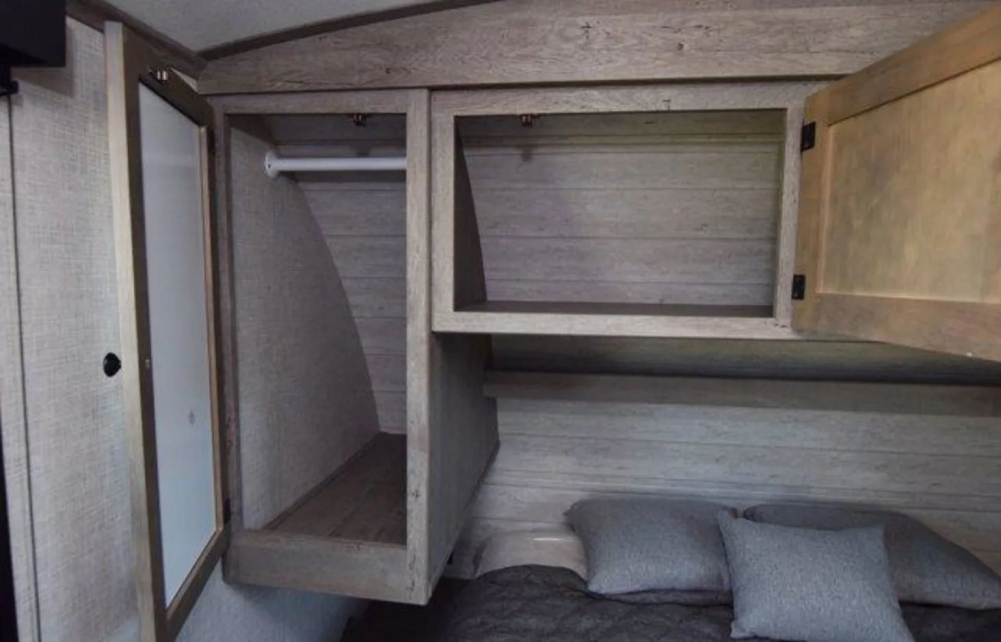 RV rental bedroom: functional storage featuring a wardrobe with hanging bar & overhead cabinet with shelves, beside a cozy bed.. Keystone RV Outback Ultra-Lite 2020