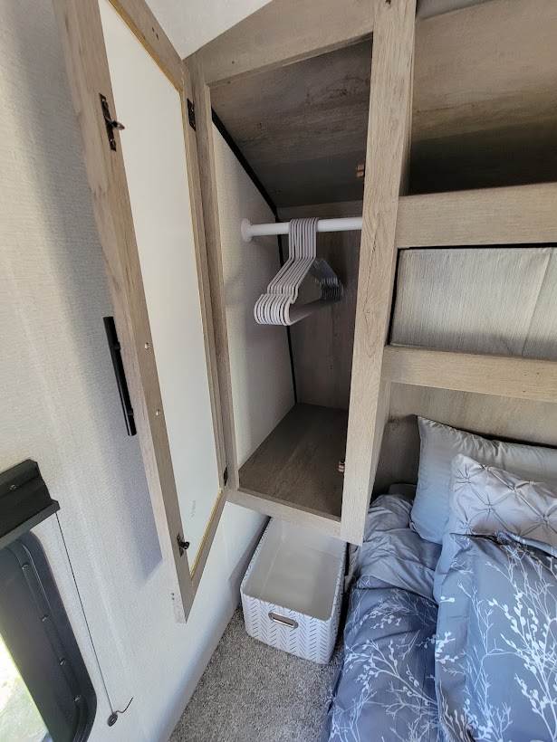 RV rental bedroom closet with hangers, storage bin, and bed for comfortable travel.. Keystone RV Springdale 2021