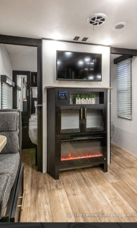 RV rental living space featuring a TV, electric fireplace, and cozy dinette area.. Forest River Cherokee Grey Wolf 2022