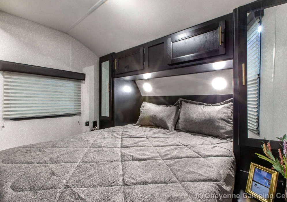 Cozy RV rental bedroom with a large bed, sleek dark cabinetry, and integrated lighting, ideal for comfortable travel.. Forest River Cherokee Grey Wolf 2022