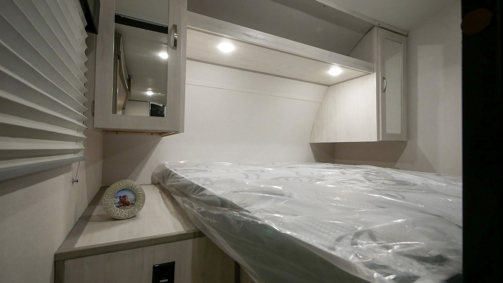 Clean RV rental bedroom with new mattress, overhead cabinets, and lighting. Ready for your next adventure!. Prime Time RV 260BHSLE 2022