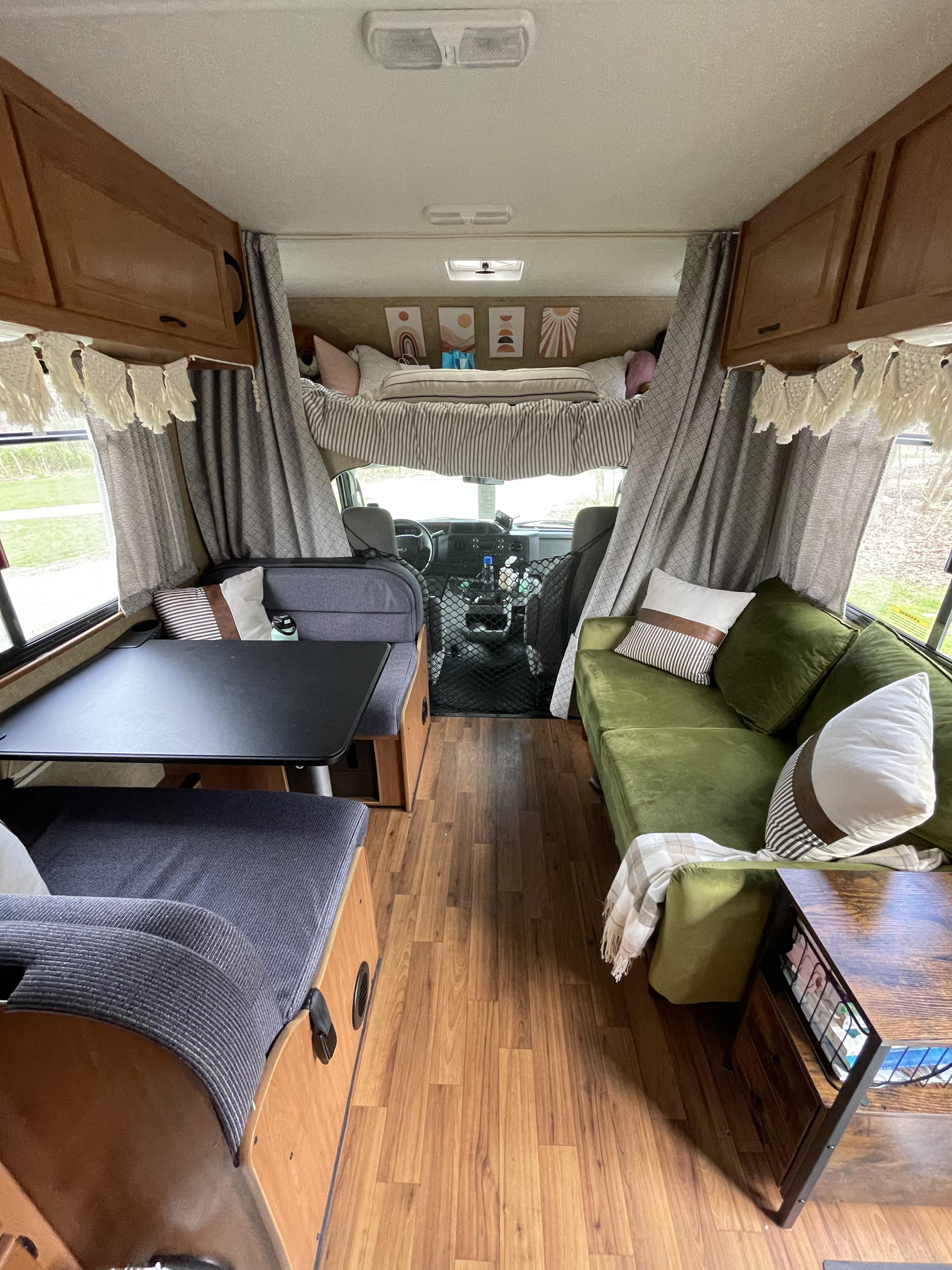 RV rental interior: A bright living area with olive green couch, dinette seating, and an overhead bunk bed.. Thor Majestic 2018