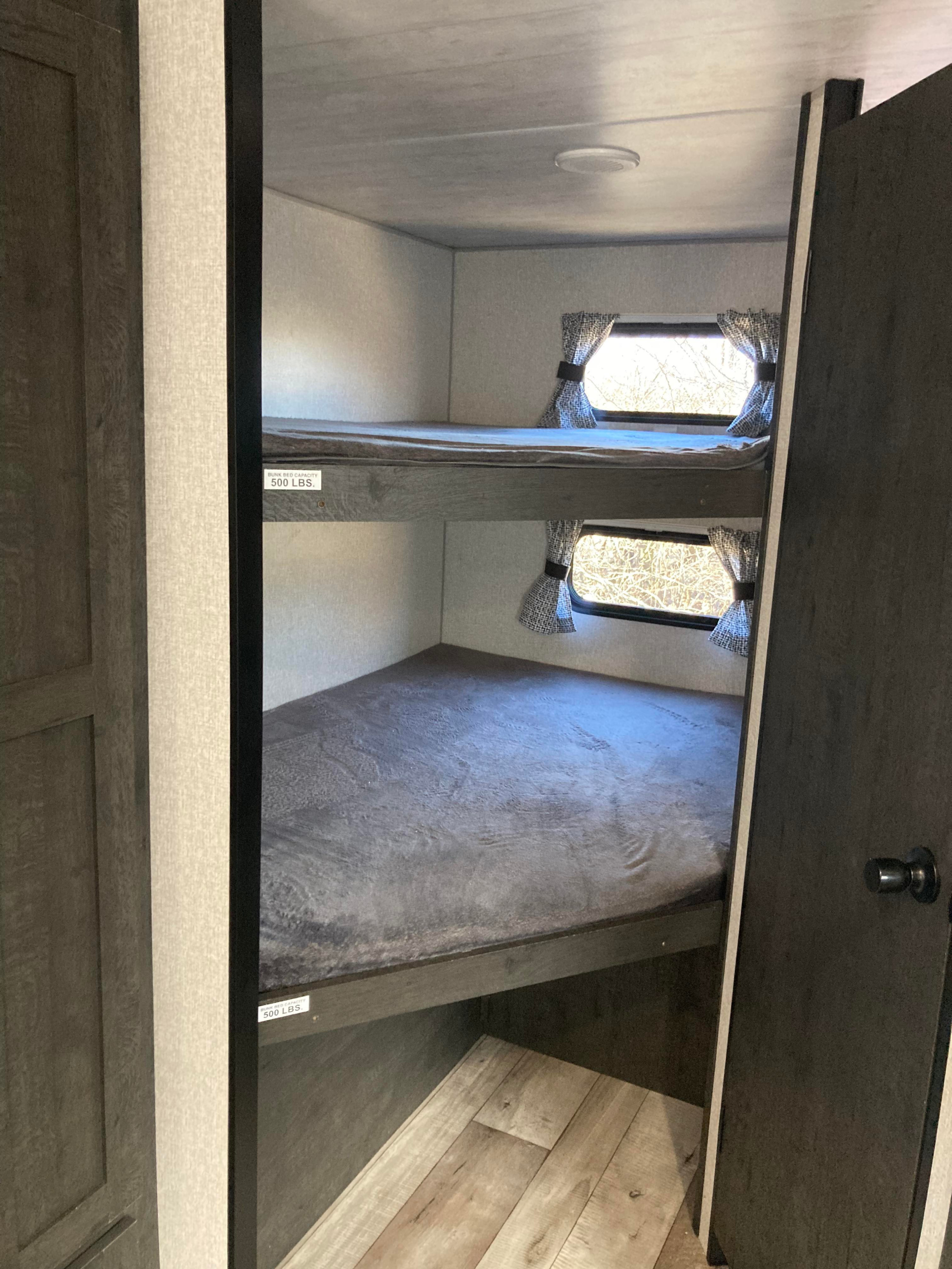 Two comfortable bunk beds inside this RV rental, complete with windows and curtains. Upper bunk 500 lbs capacity.. kz SE 271 2021