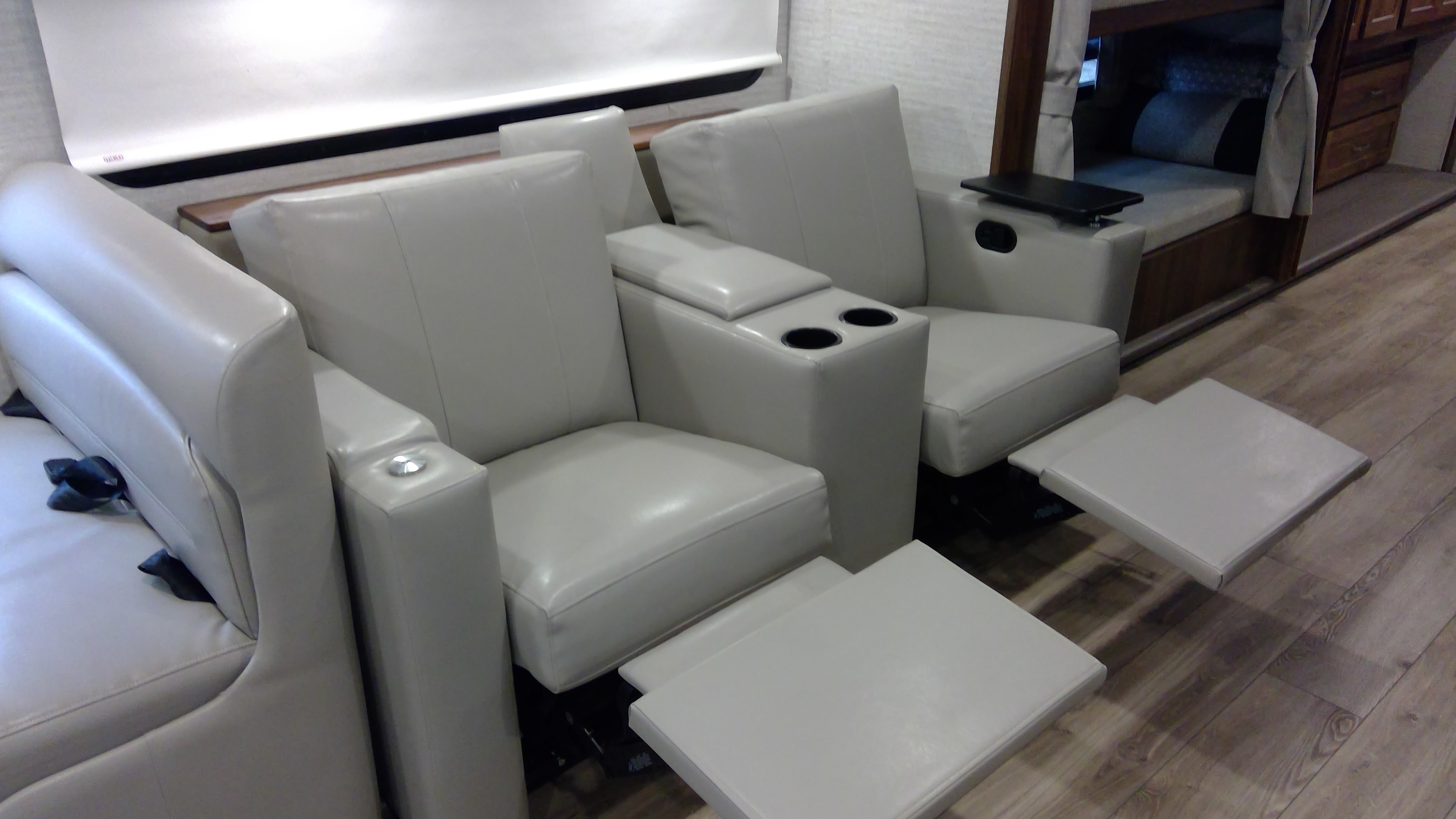 Comfortable RV rental interior featuring light-colored reclining seats with extended footrests and cup holders.. Winnebago Forza 2022