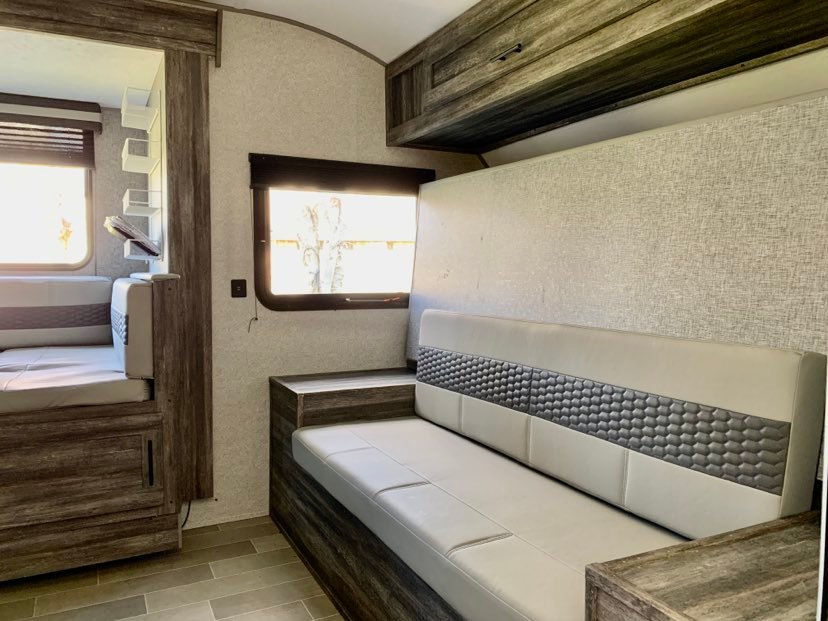 Inside a modern RV rental: light-filled interior with comfortable sofa and dinette seating, wood-look finishes.. Forest River Salem FSX PLATINUM 2020