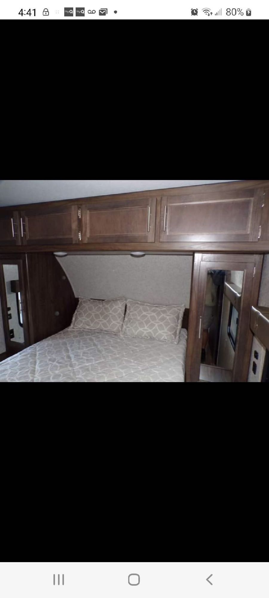 Experience comfort in this RV rental bedroom, featuring a bed with patterned pillows, overhead cabinets, and mirrored storage.. Forest River Wolf Pack 2019