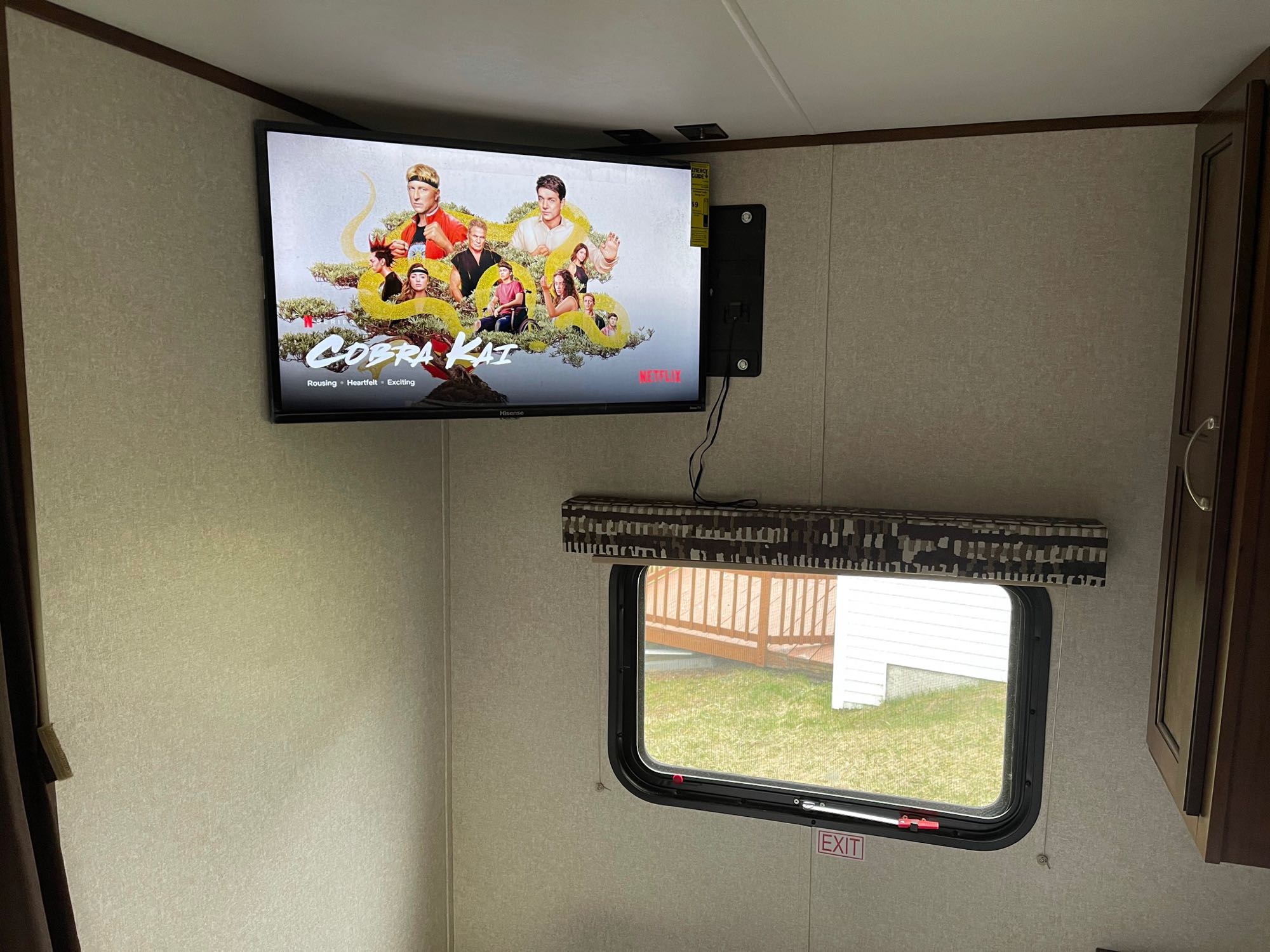 RV rental interior showing a mounted TV displaying 'Cobra Kai' on Netflix, with a window and exit sign.. Jayco Jay Flight SLX 2017