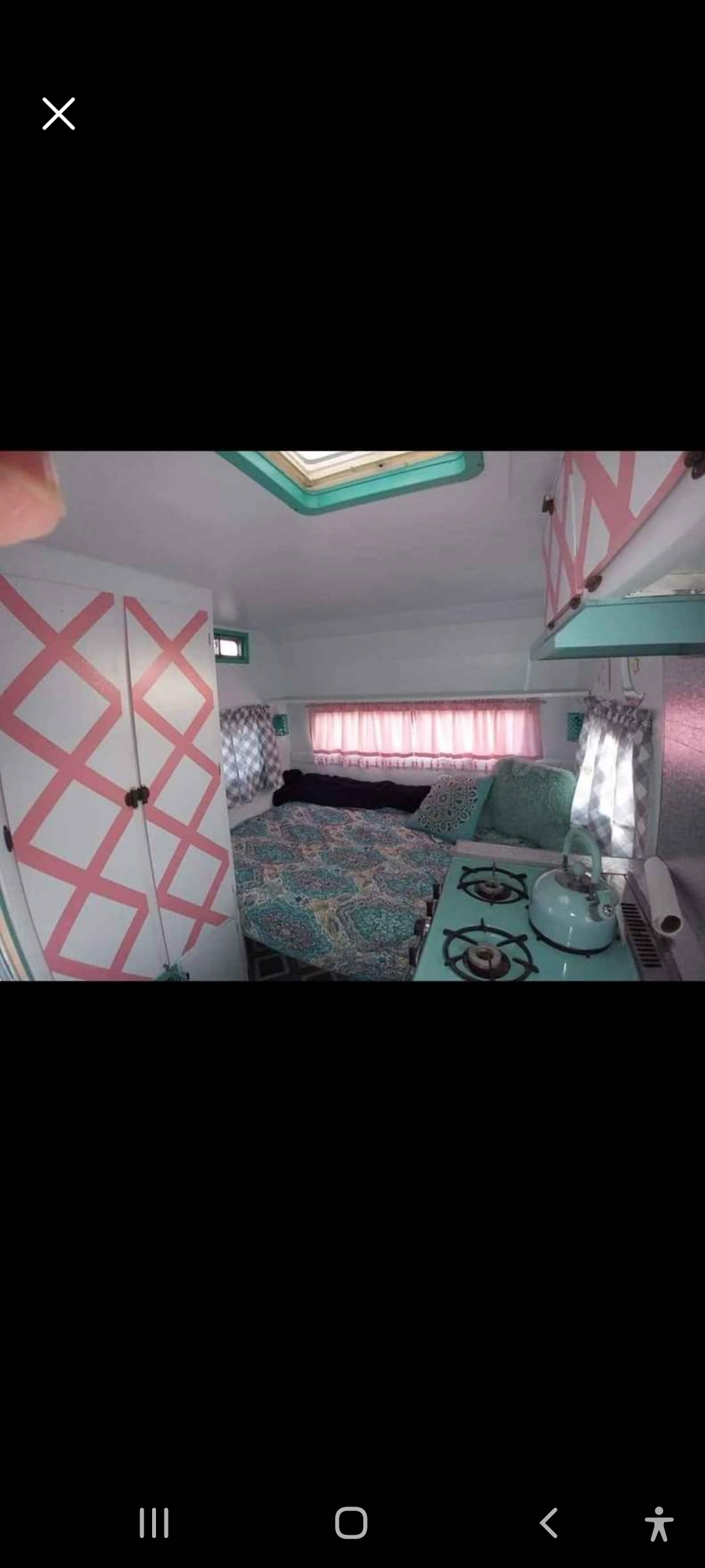 Retro RV rental interior: cozy bed, teal stovetop, pink curtains & geometric cabinet design.. Red Dale Red Dale 1966