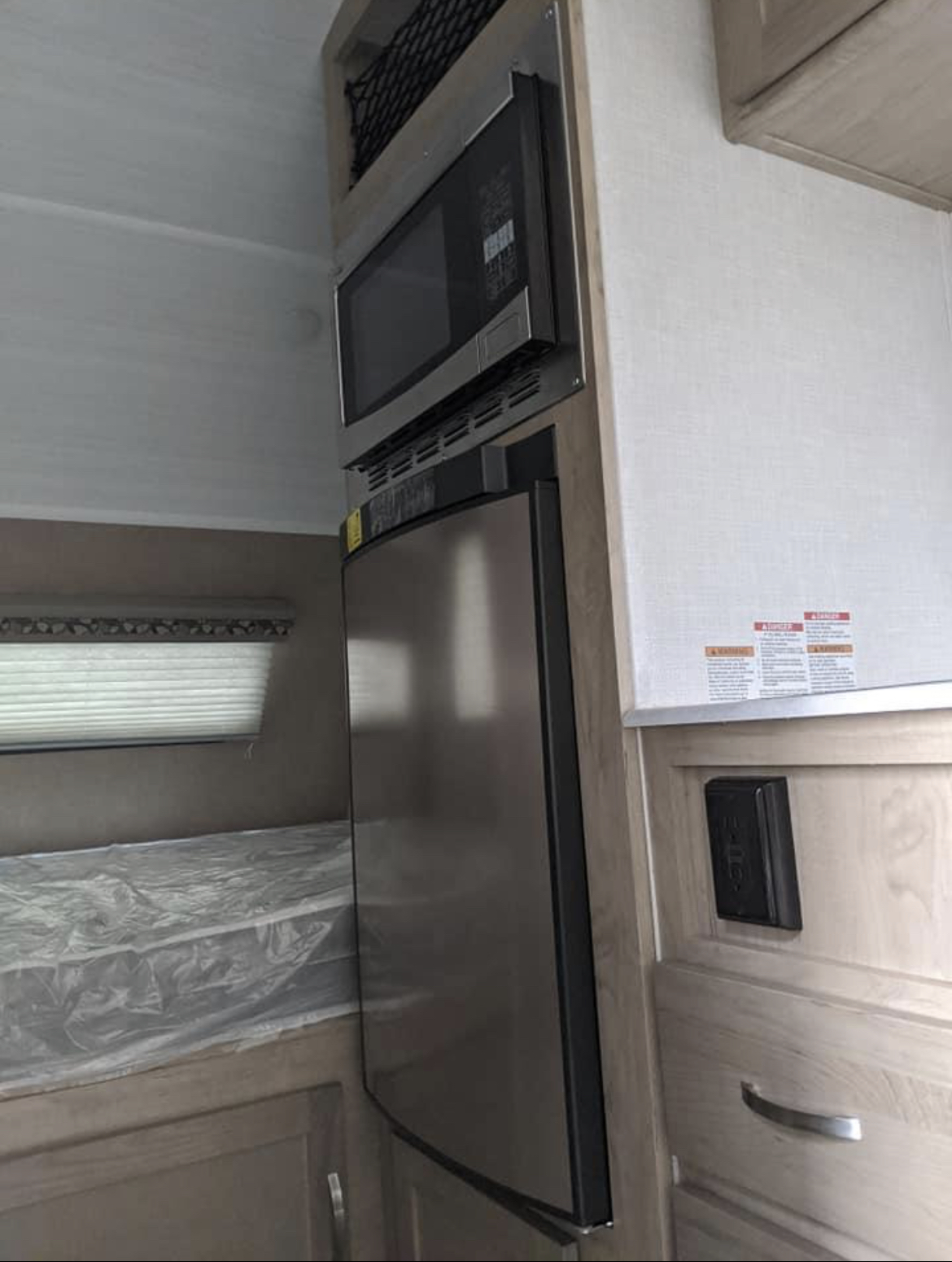 An rv rental interior featuring a built-in microwave, refrigerator, and bed. Compact living on the go.. Forest River R-pod 171 2020