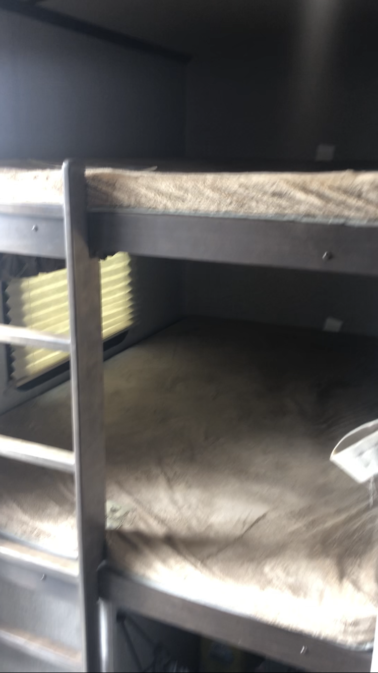 RV rental interior shows cozy bunk beds with light mattresses and a window, a compact sleeping area for travelers.. Keystone RV Laredo 2019