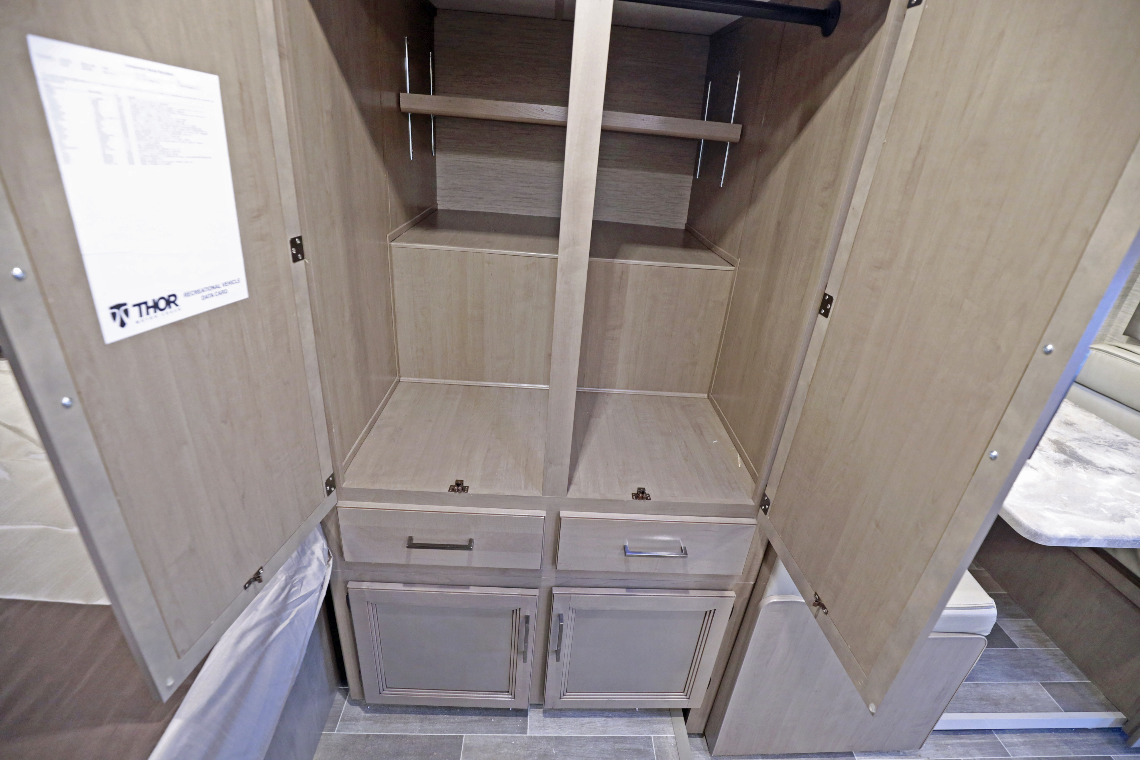 Open RV rental wardrobe showcasing light wood shelves, hanging rod, drawers, and cabinets. Ample storage.. Classe C 24-26 pieds avec extension(s) 2022