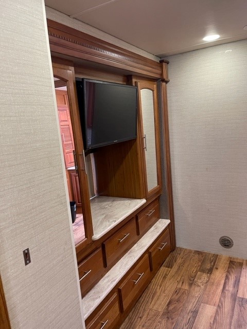 RV rental interior. Spacious built-in TV unit with drawers & mirrored cabinets for storage in this RV bedroom.. Jayco Precept 2017