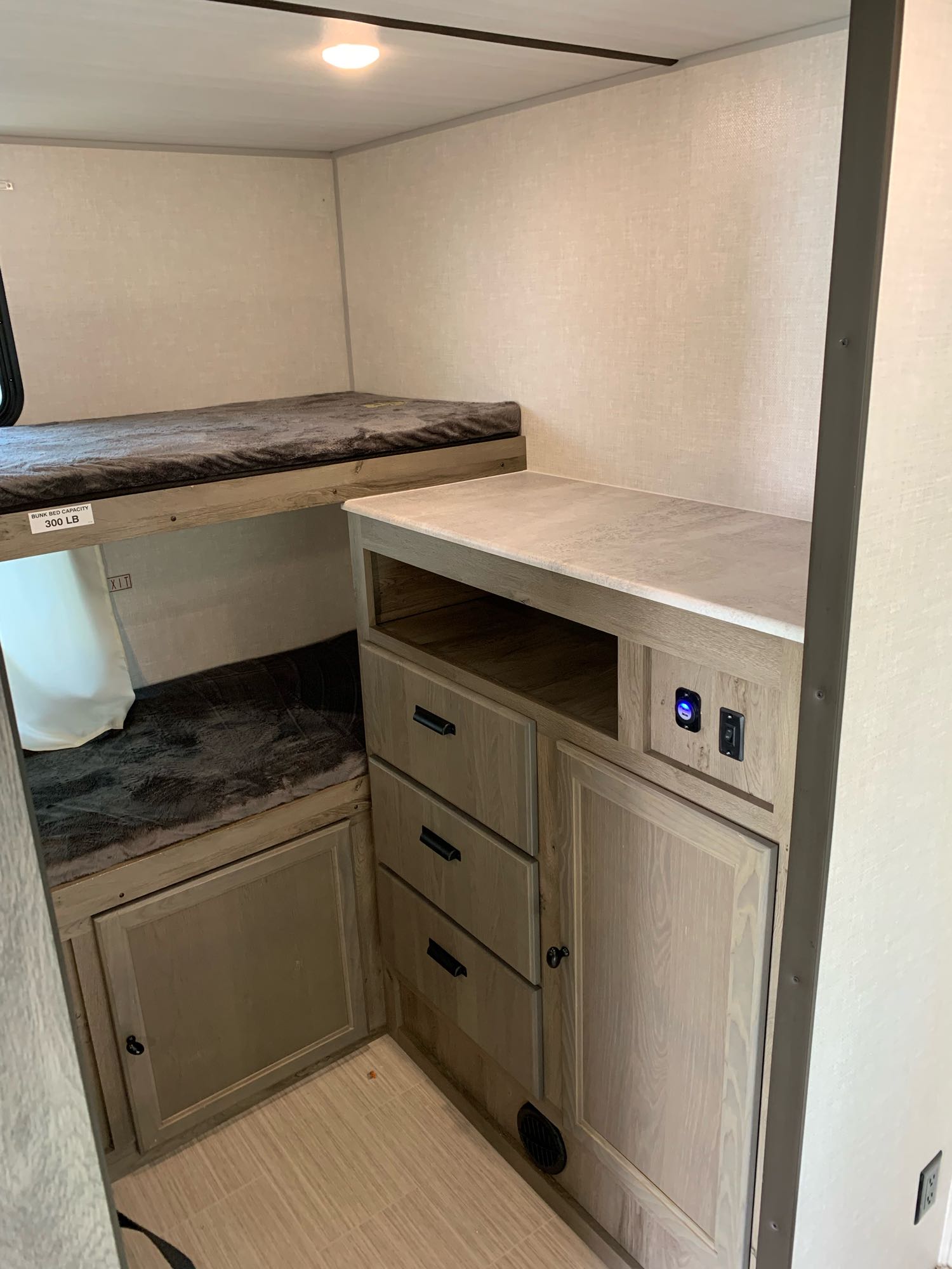 Cozy RV rental interior with bunk beds, built-in storage, and charging station, perfect for family adventures.. Forest River Surveyor Legend 296QBLE 2021