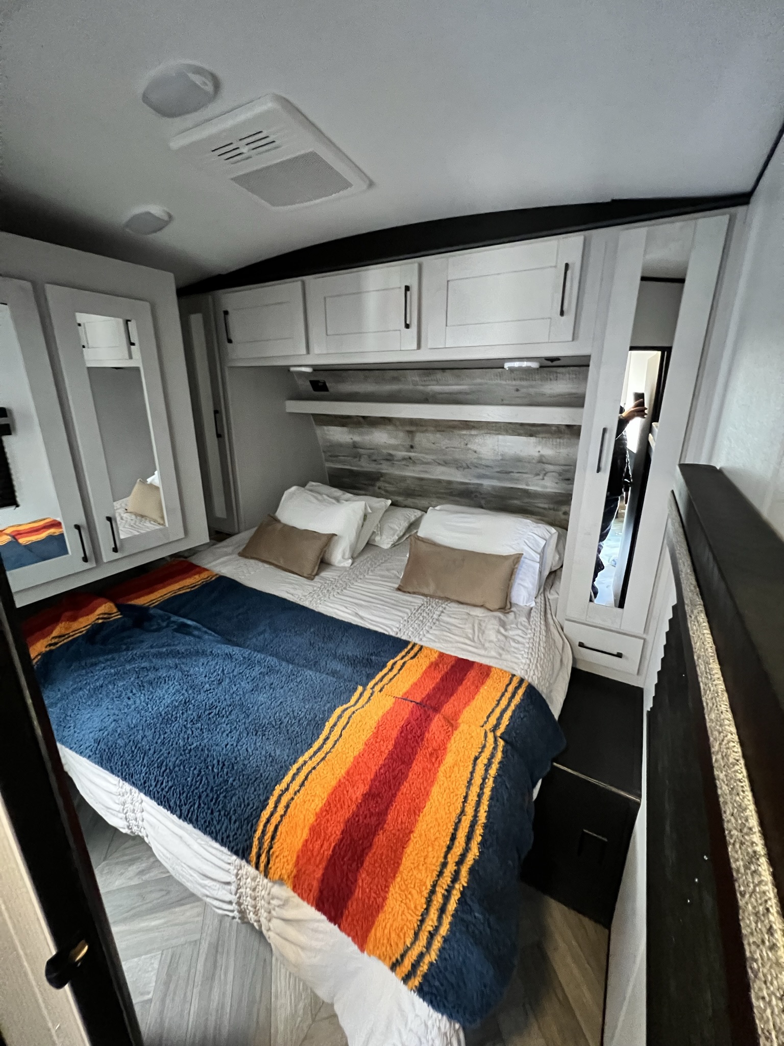 Cozy RV rental bedroom featuring a modern bed with a colorful blanket, built-in storage, and sleek interior design.. Heartland Torque 2022