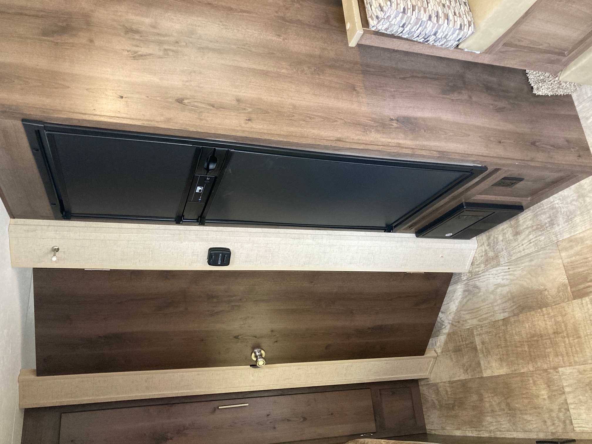 RV rental interior showing a built-in refrigerator, wooden wall panels, and a light in the sleeping area.. KZ Escape 2017