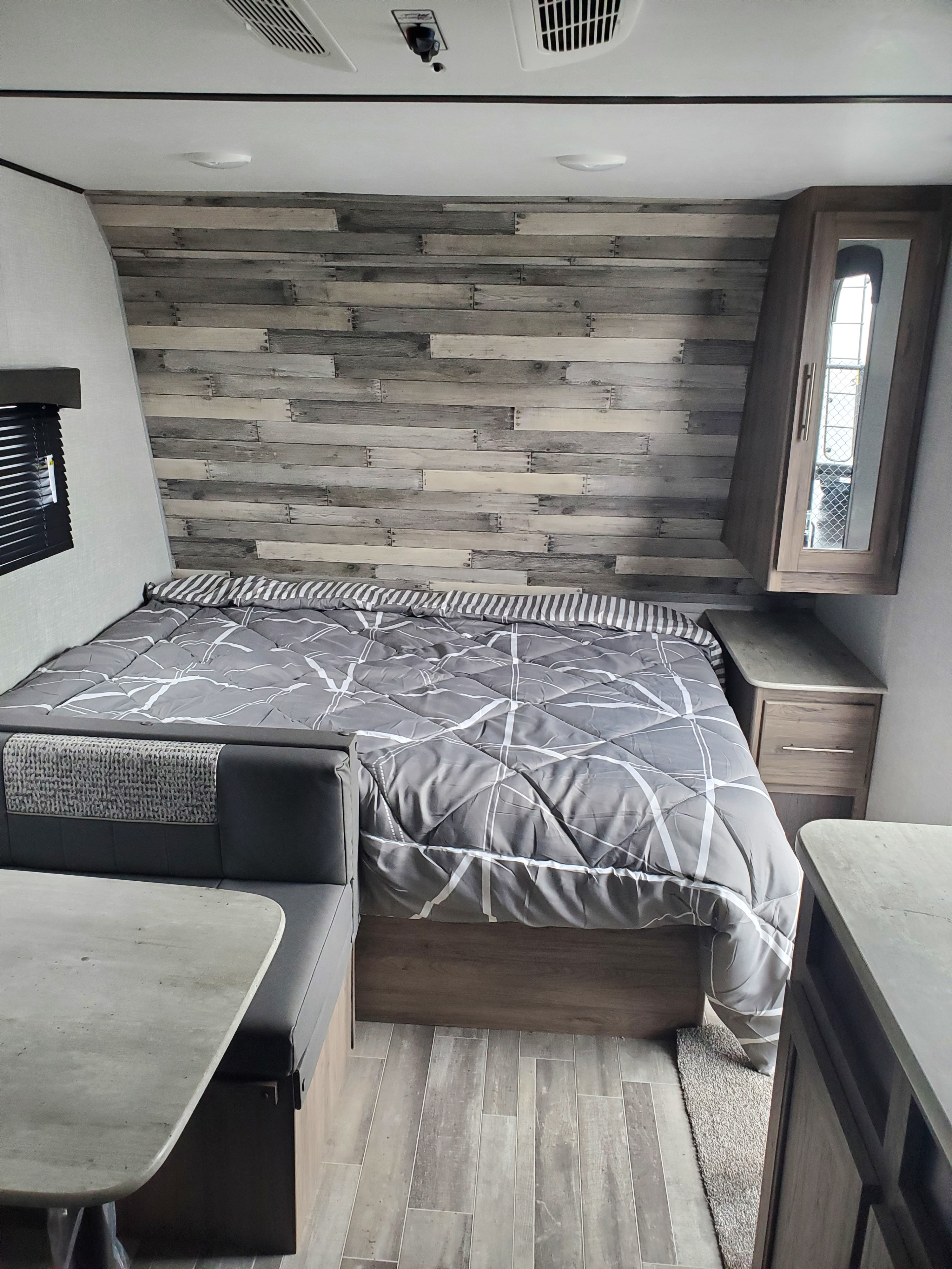 Compact rv rental interior featuring a bed, dinette, and modern wood-look decor.. Crossroads RV Zinger 2021