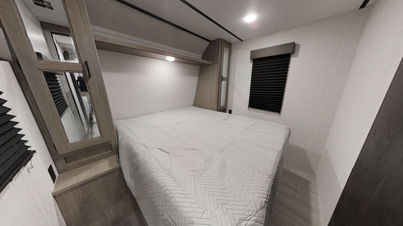 Clean and cozy RV rental bedroom. Features a comfortable bed, built-in storage, and window with blind, ideal for travel.. Keystone RV Hideout 2022