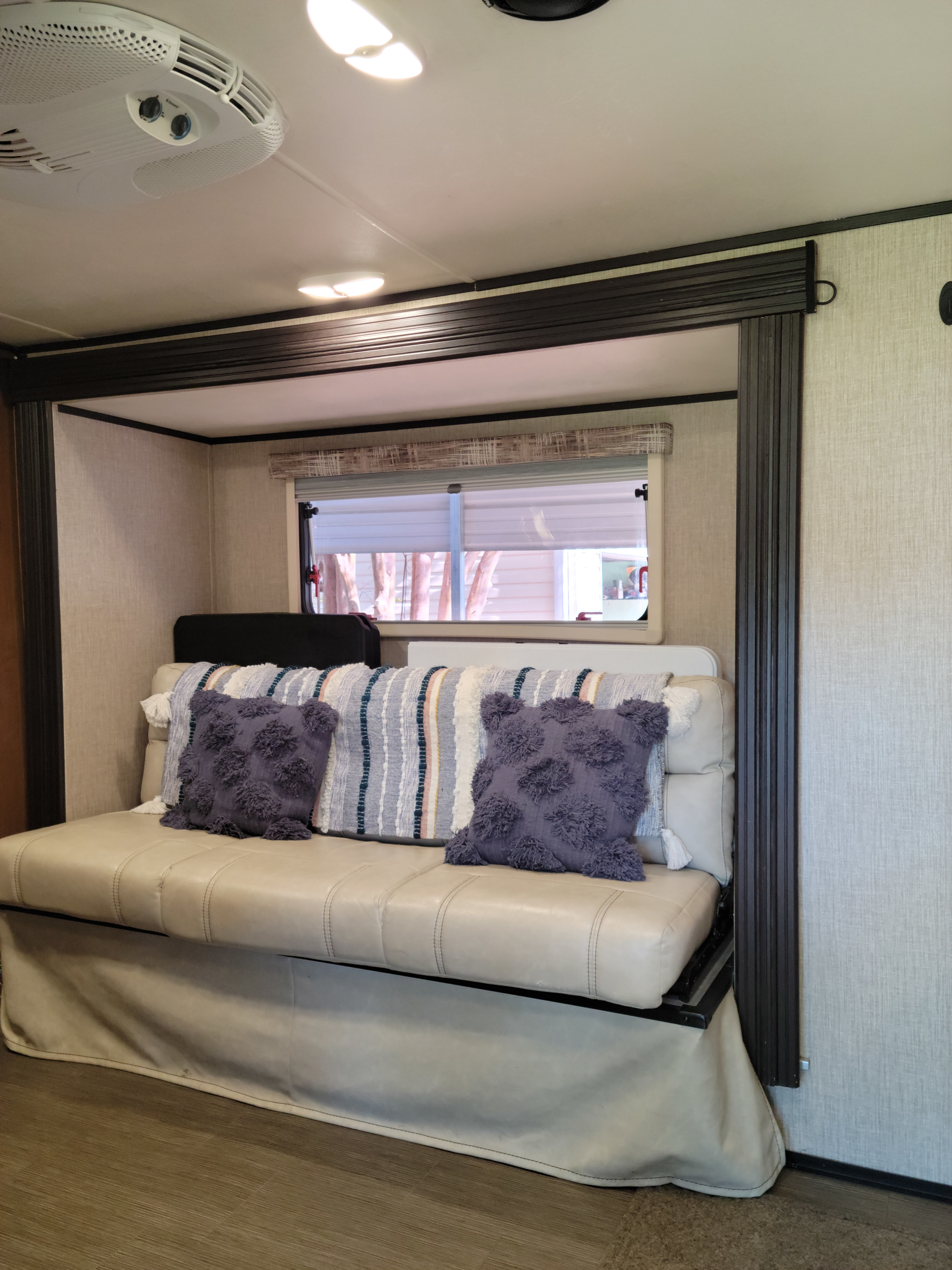 Inside this cozy RV rental: a convertible sofa bed with decorative pillows, a window, and overhead AC. Ready for adventure!. Other Other 2018