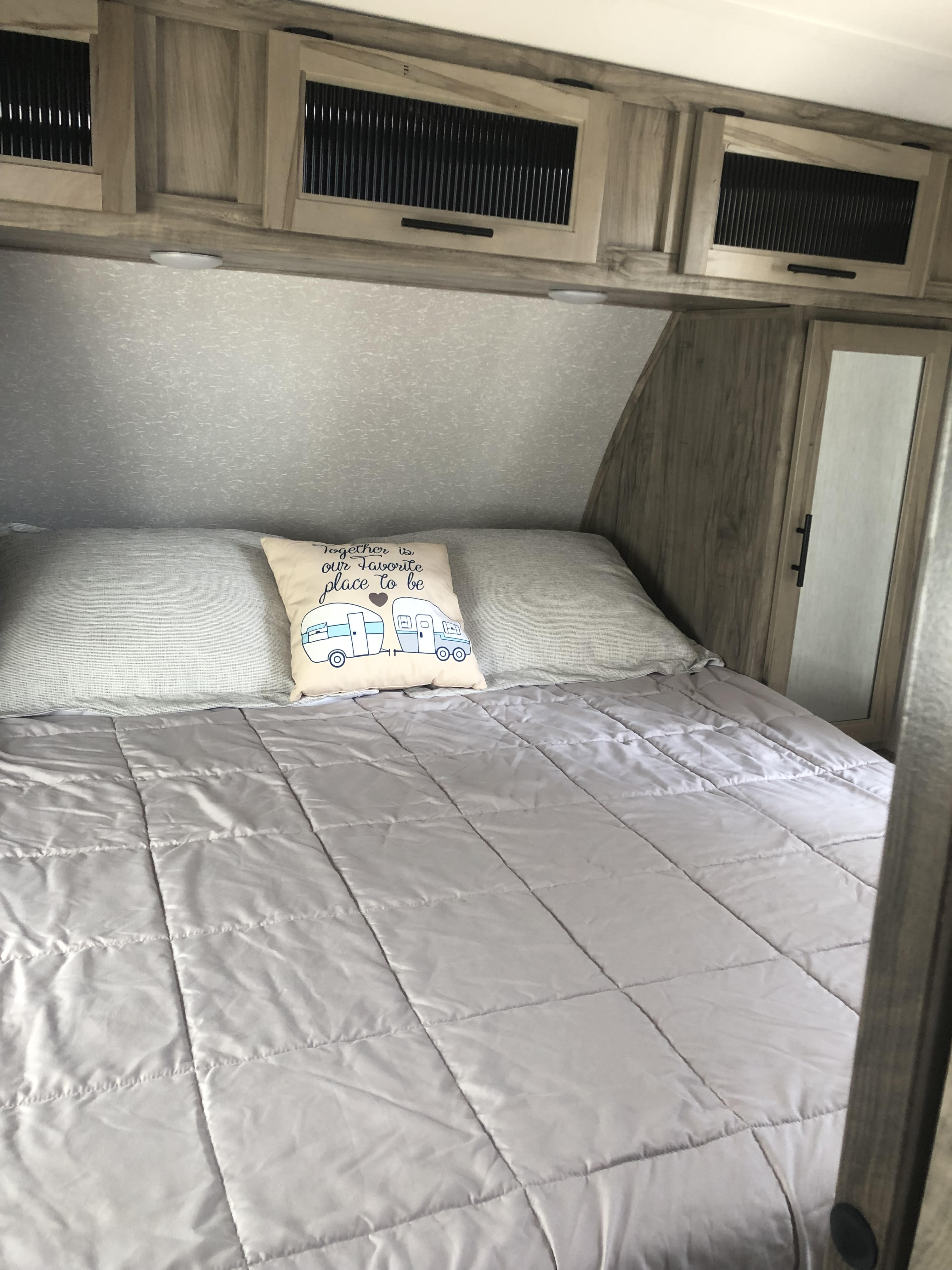 Relax in this cozy RV rental bedroom. Features a comfy bed, camper pillow, and slatted overhead storage cabinets.. Forest River Cherokee Alpha Wolf 2022
