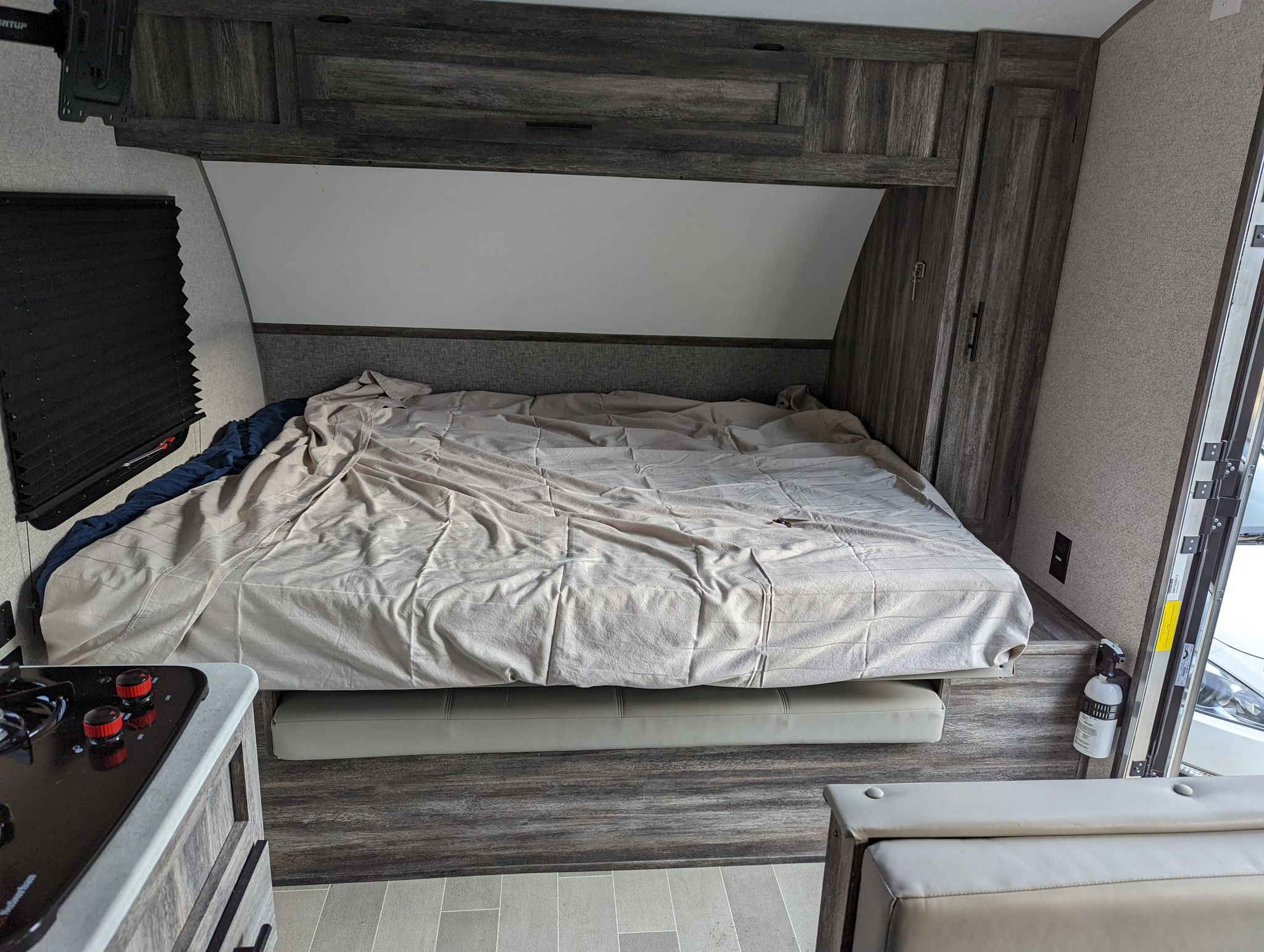 An RV rental bedroom featuring a spacious bed, overhead storage, and adjacent kitchen area.. Forest River Salem FSX 2021