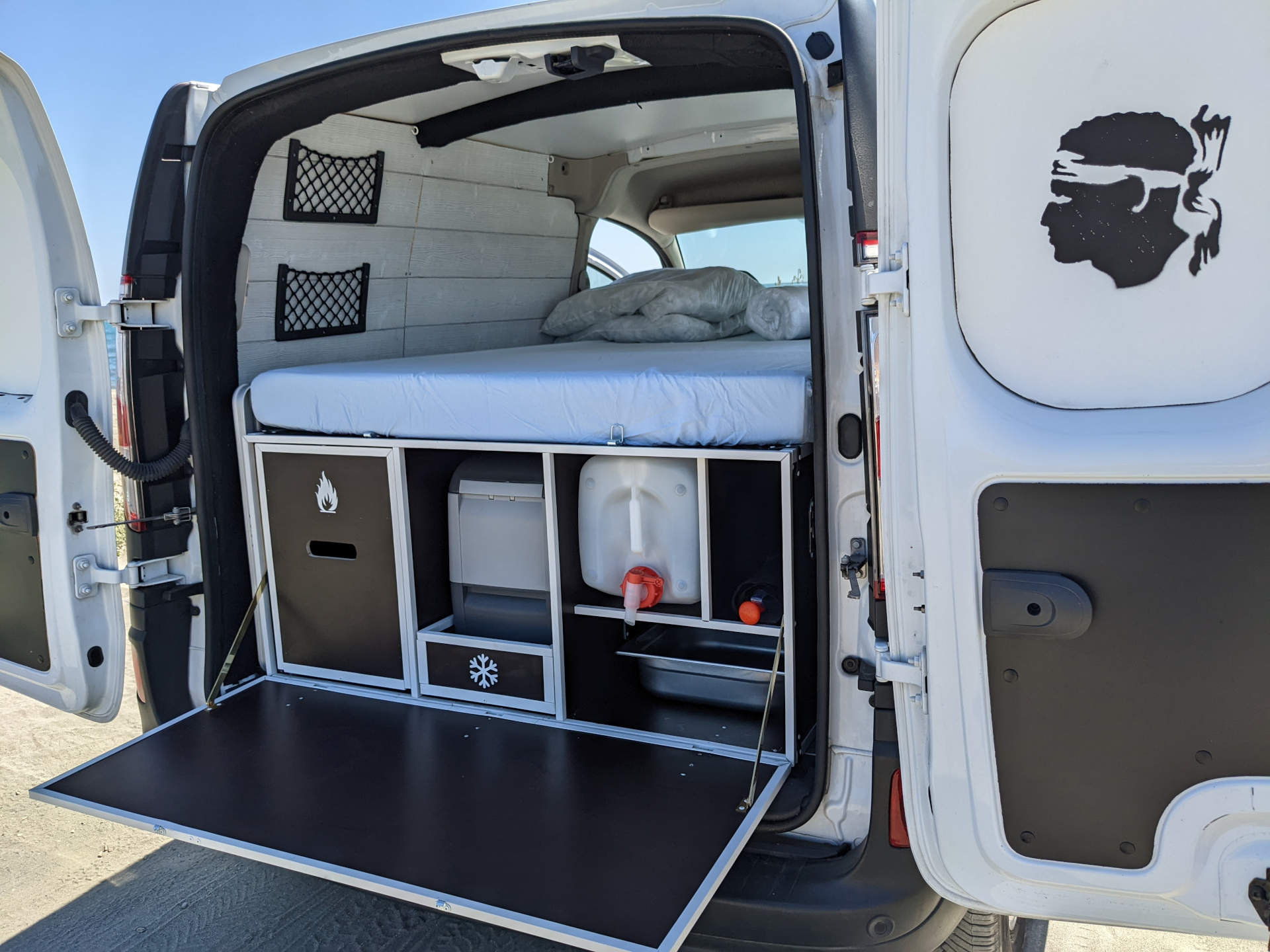 RV rental: Camper van interior with bed, storage, water tank, portable toilet, and fold-down counter for camping.. Renault KANGOO 2019