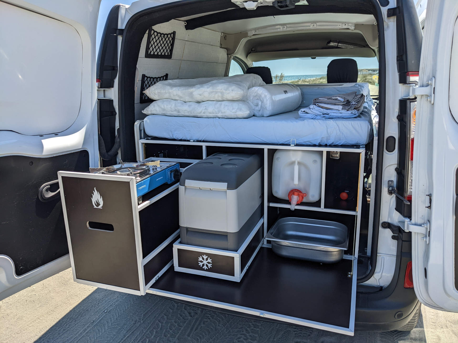 Compact RV rental camper van features a pull-out kitchen with stove & sink, built-in cooler, and comfortable bed.. Renault KANGOO 2019
