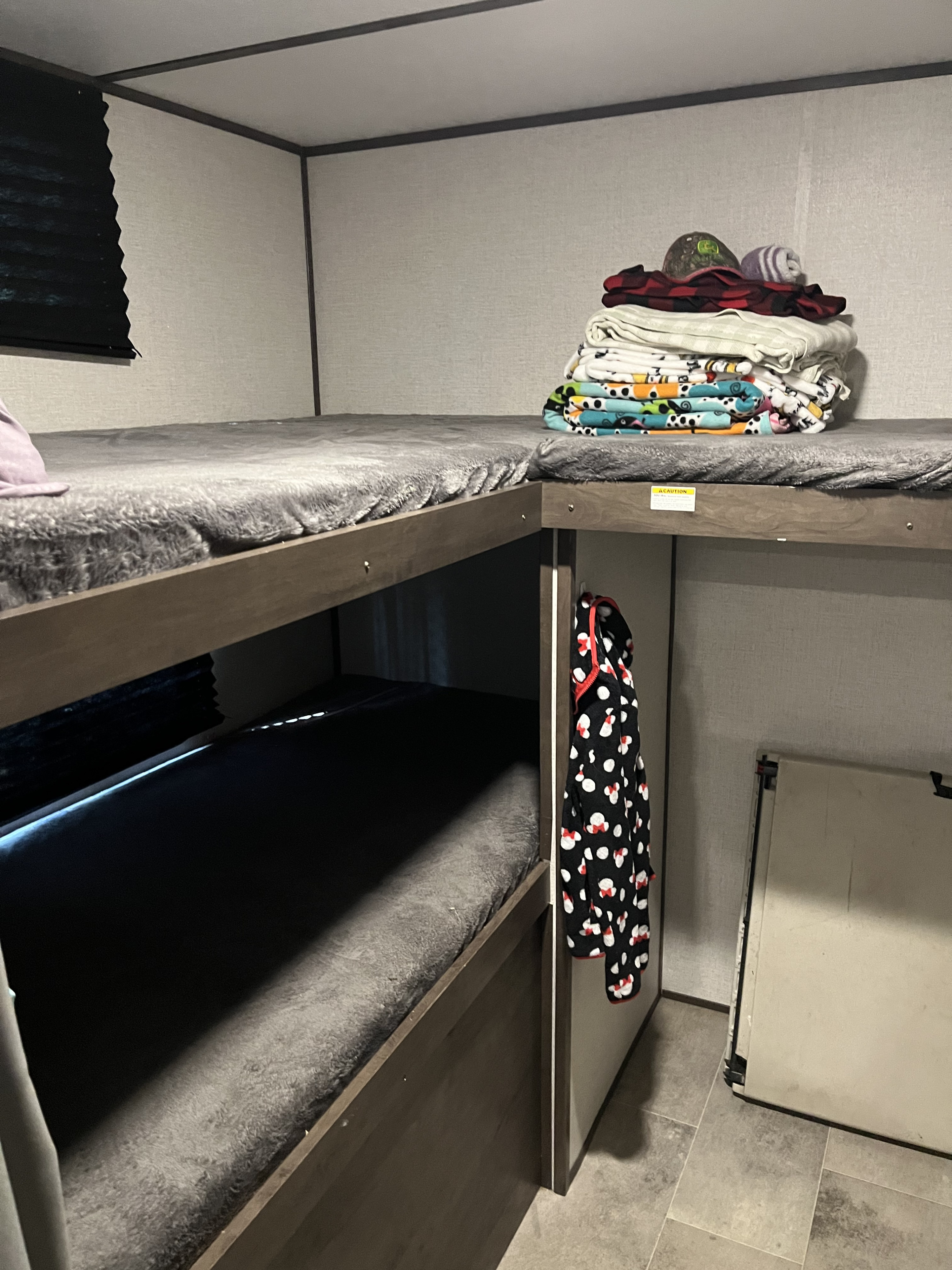RV rental bunk beds: a cozy interior sleeping area with stacked blankets and a hanging robe.. Coleman QBWE295 2021