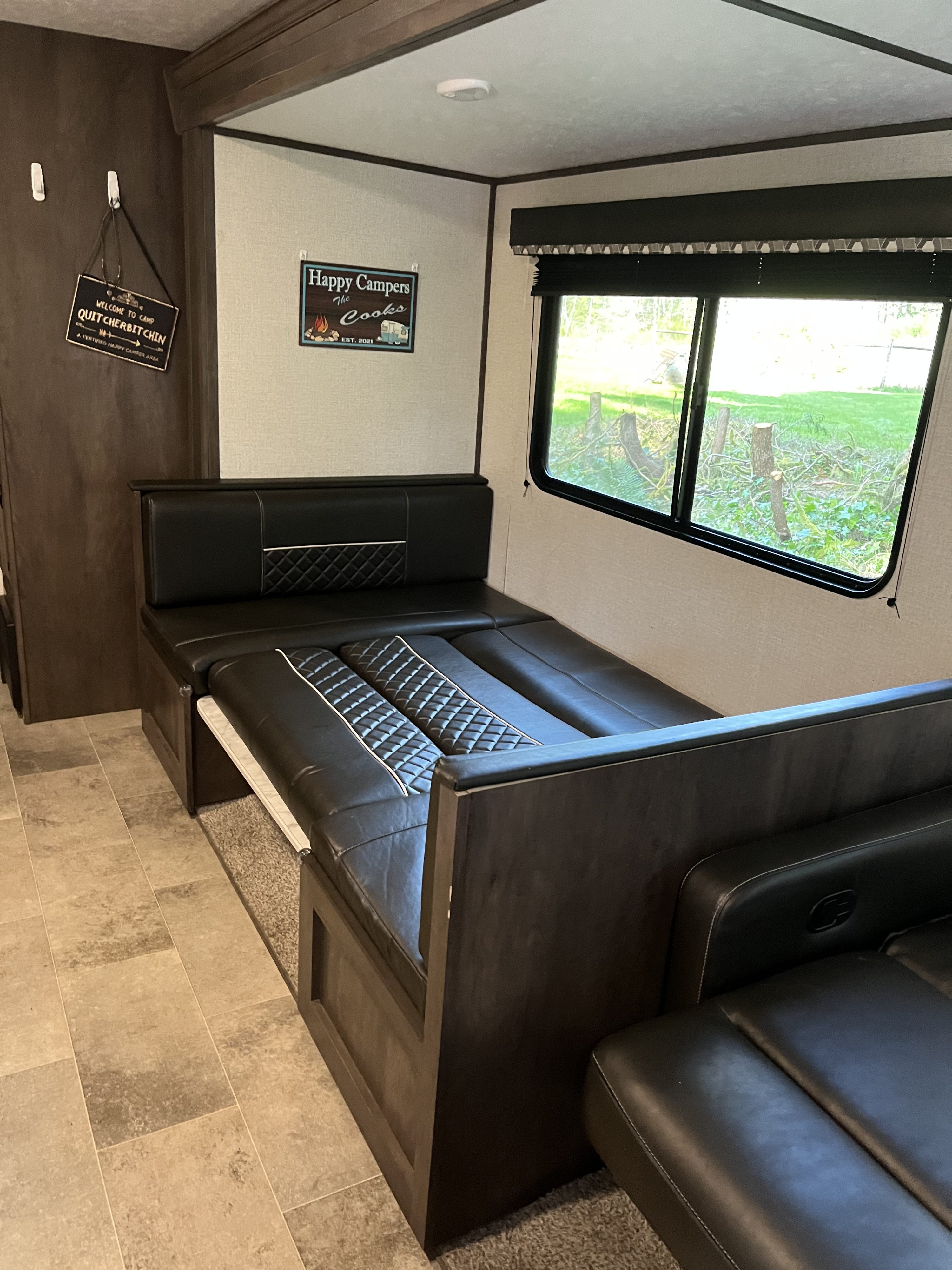 RV rental interior with a convertible black dinette bed and camp-themed decor, perfect for travel.. Coleman QBWE295 2021