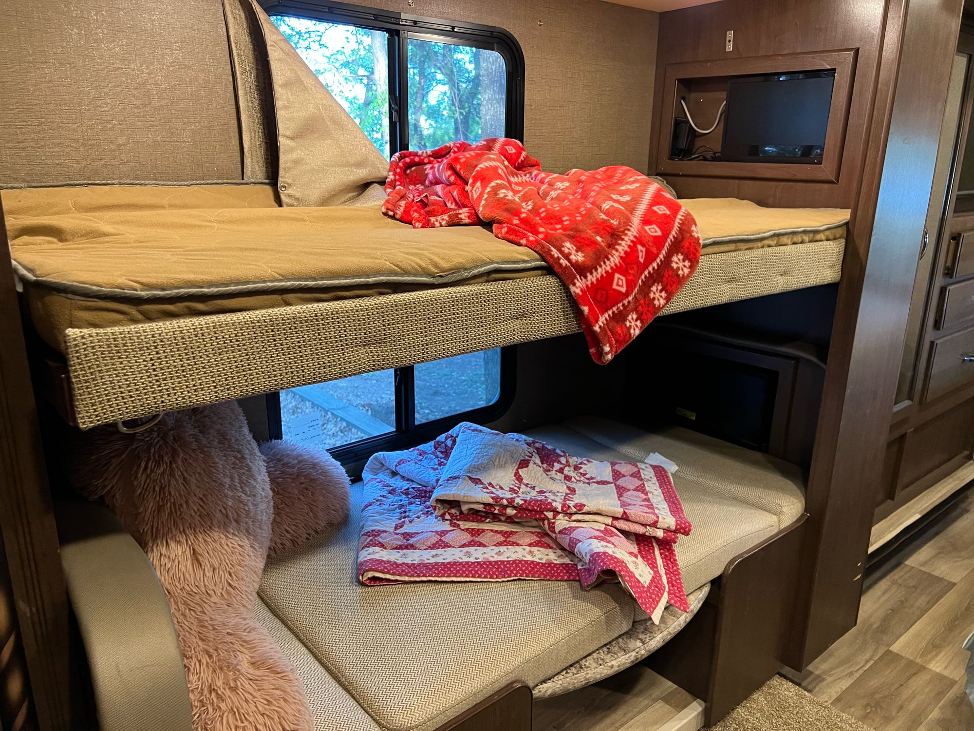 Inside an RV rental: two comfy bunk beds with blankets, a large stuffed animal, & TV for a cozy travel experience.. Thor Freedom Elite 2017