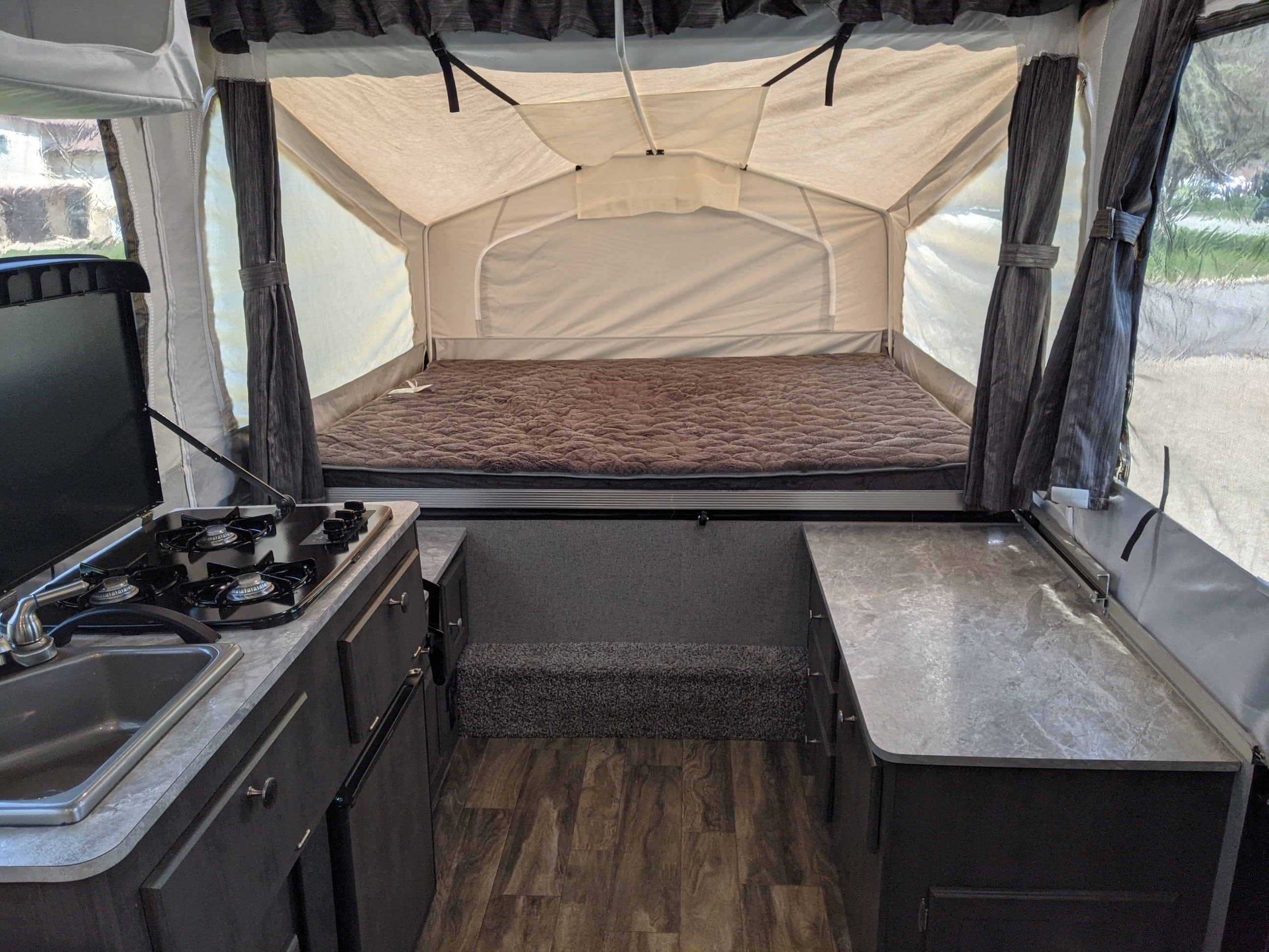 Interior of a pop-up rv rental with a full bed, stovetop, sink, & cabinets for your next camping trip.. Forest River Rockwood Freedom 2020